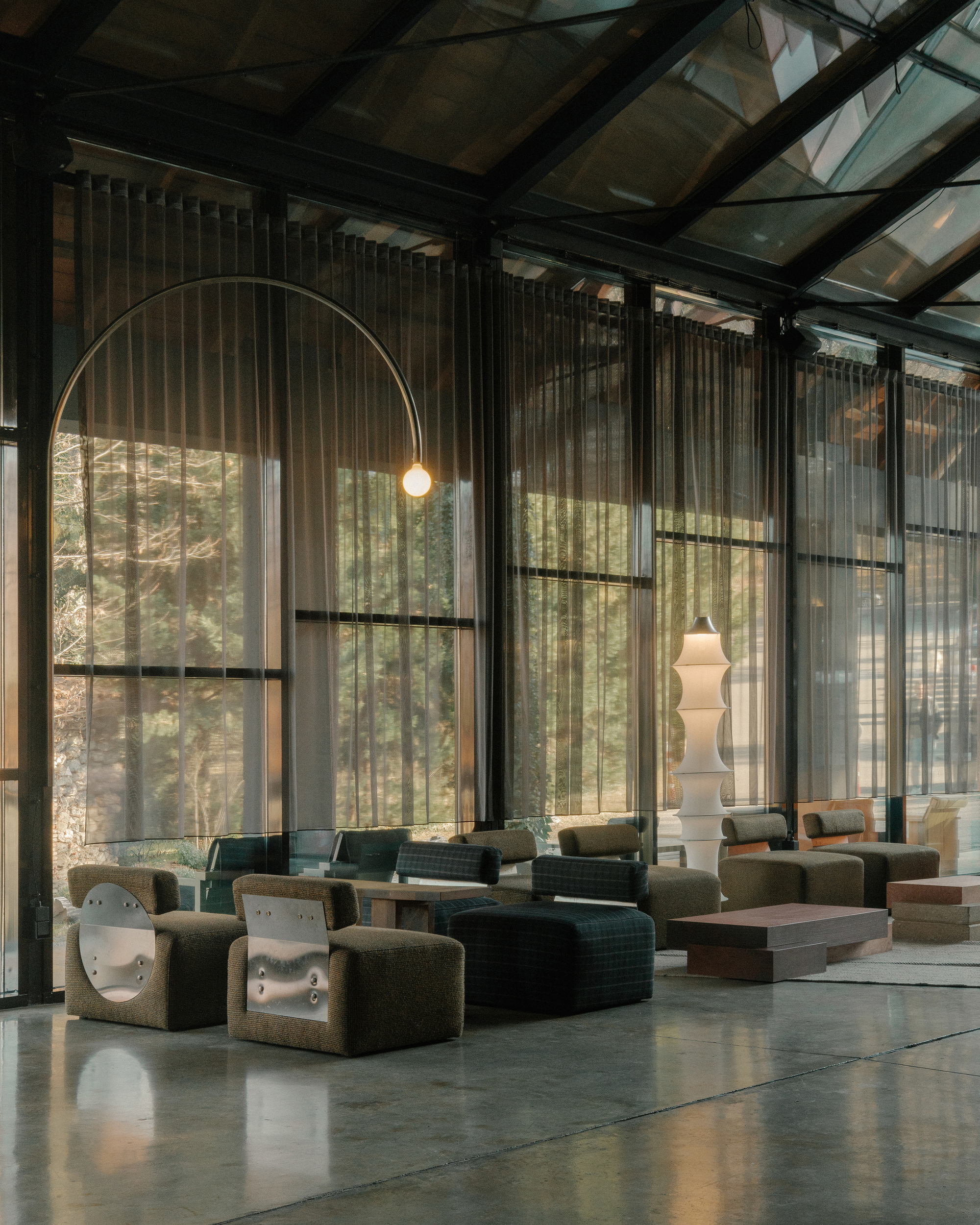 Seating area beneath an arched pendant light with filtered daylight through sheer curtains
