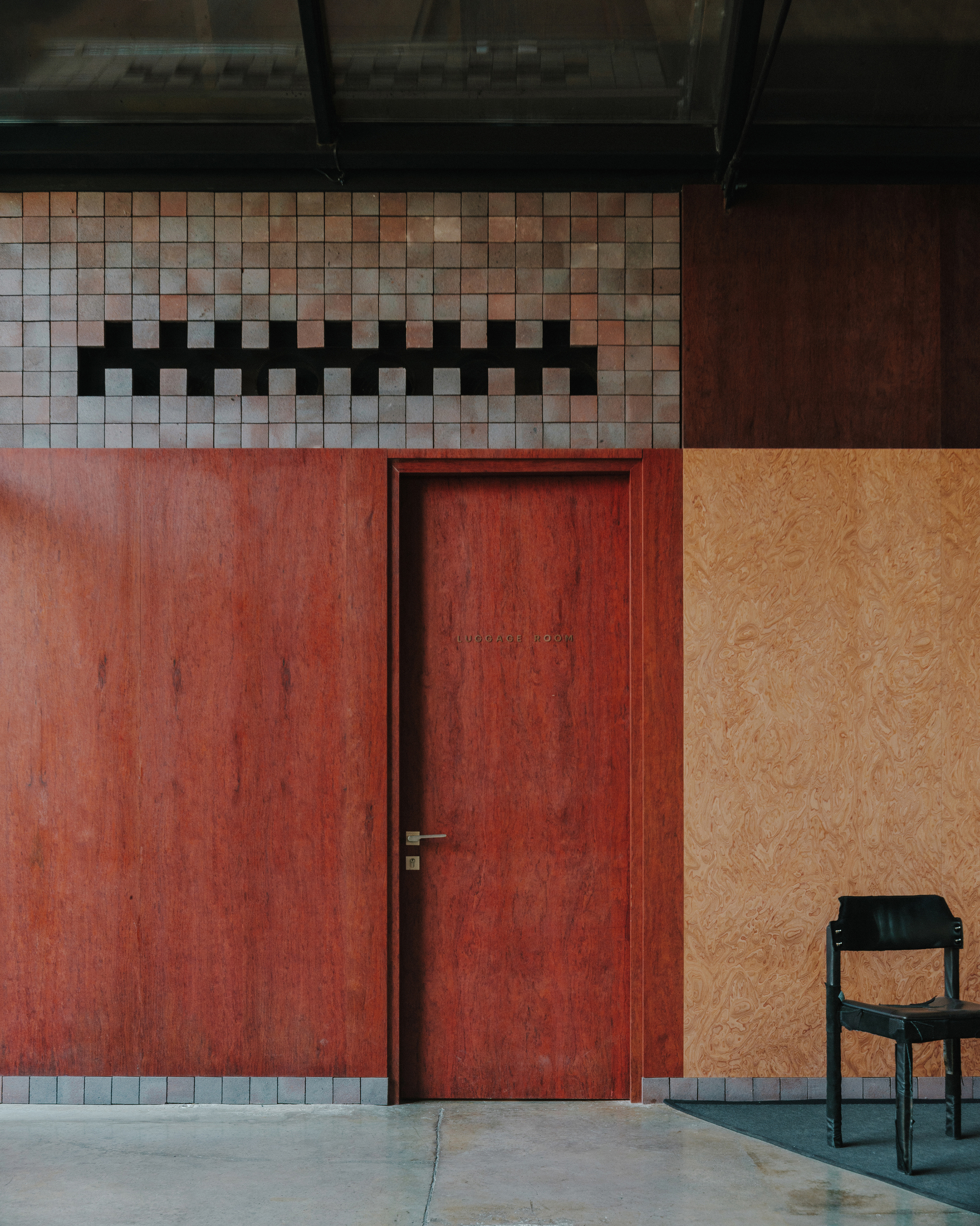 Red plywood door with mosaic tile clerestory band and adjacent plywood wall panel