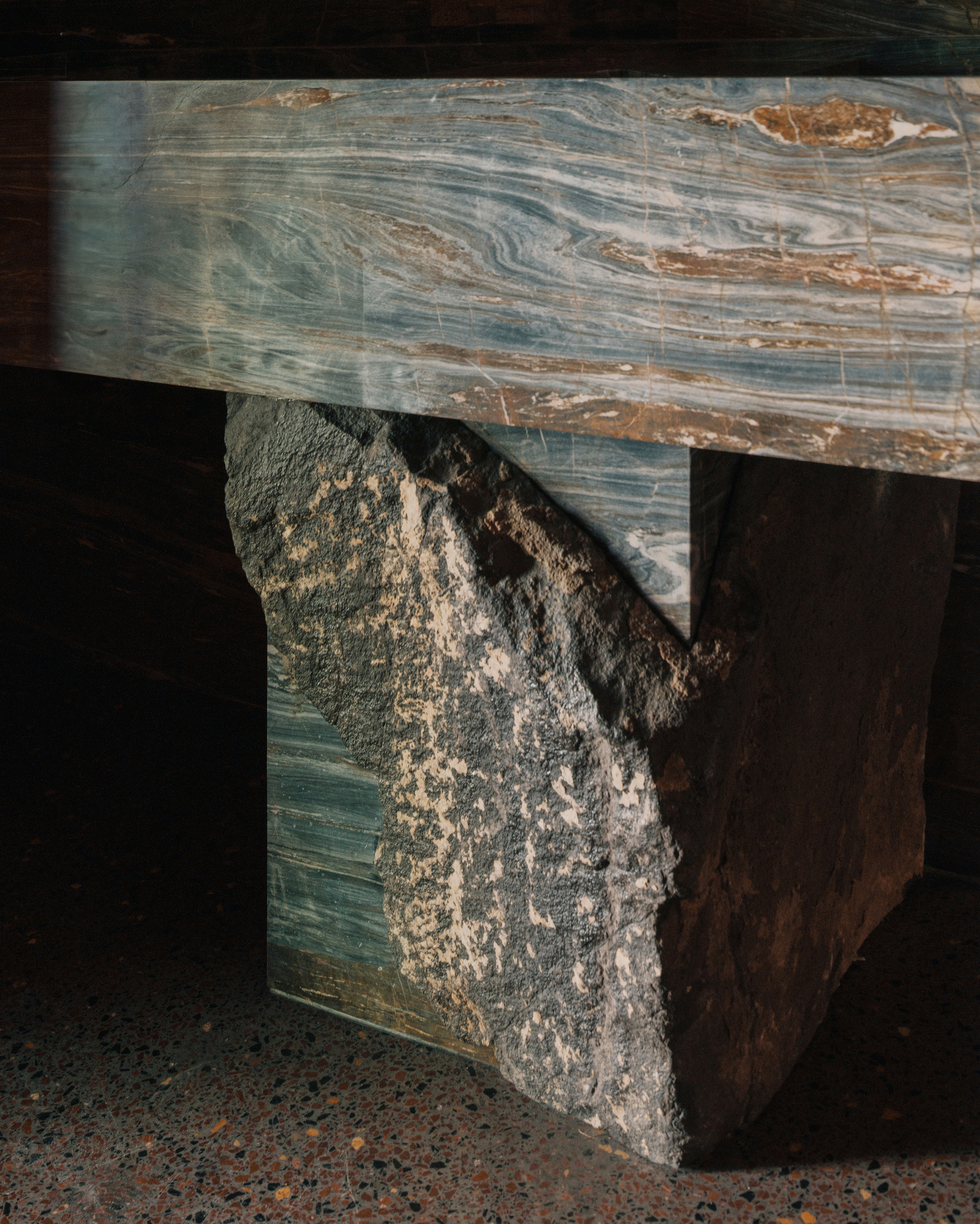 Close-up of marbled stone bench with rough quarried block base on terrazzo flooring