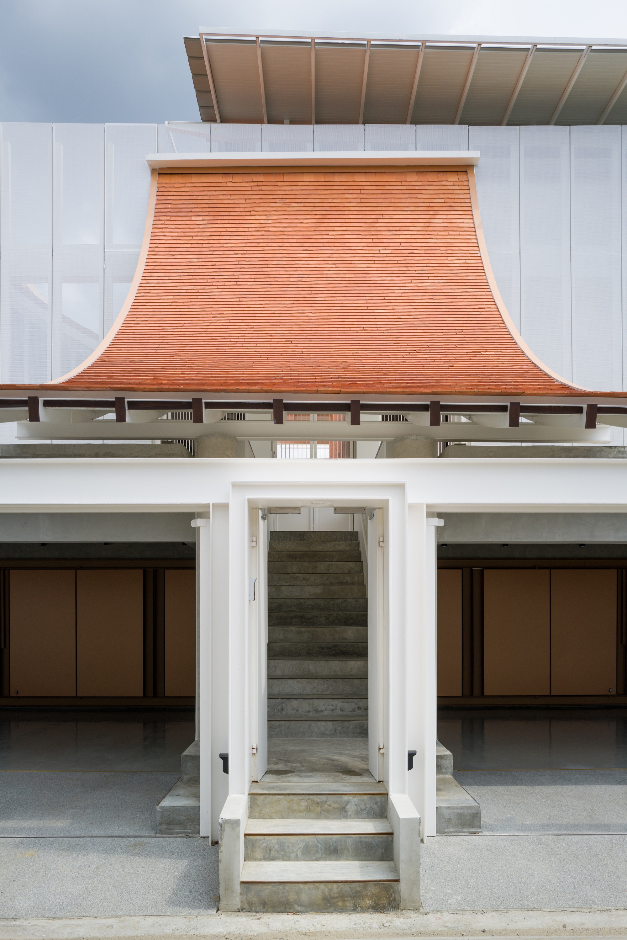 Central concrete staircase framed by white walls beneath the curved terracotta roof