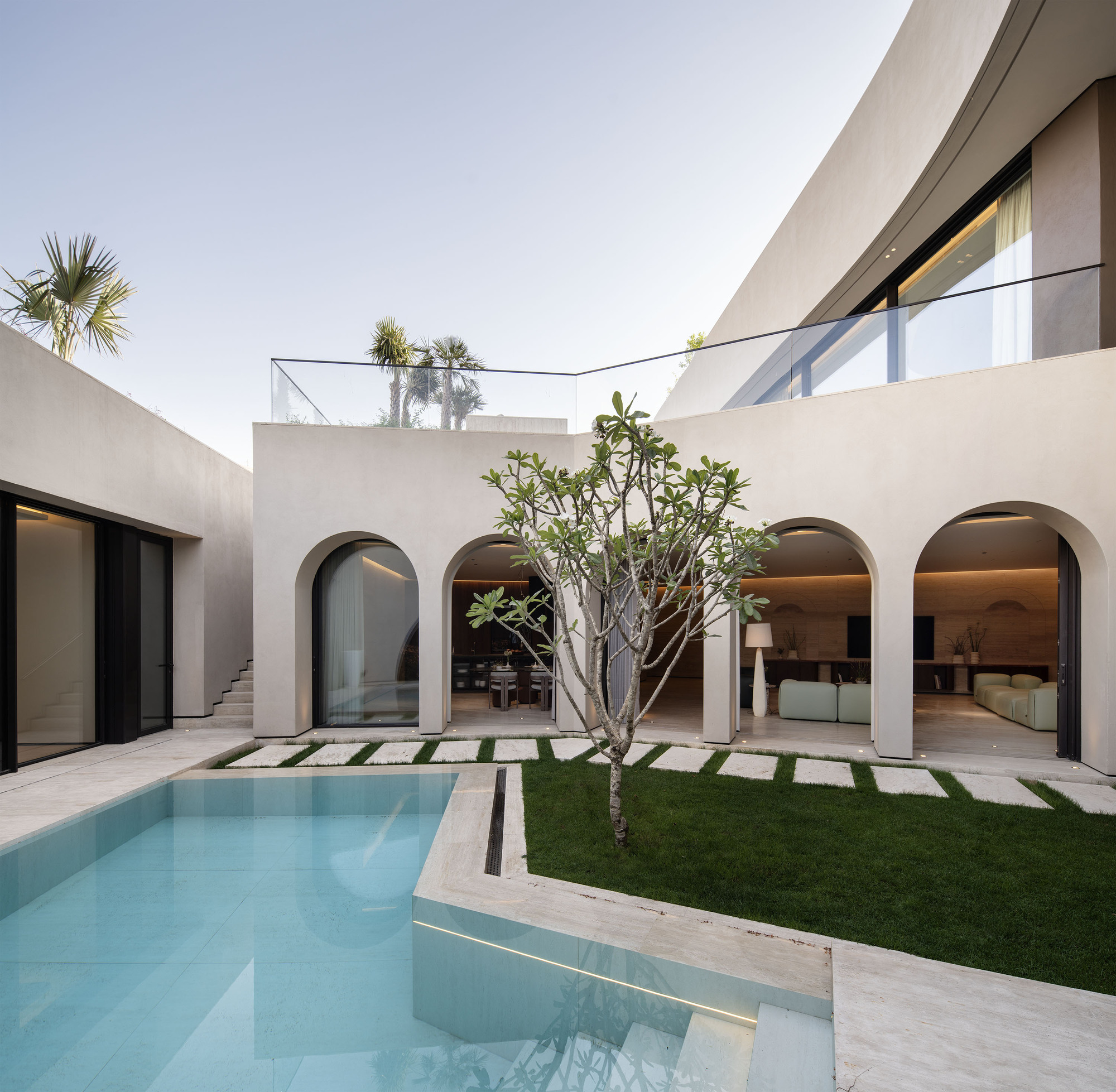 Interior courtyard with rectangular pool and lawn grid pavers beside arched openings at dusk