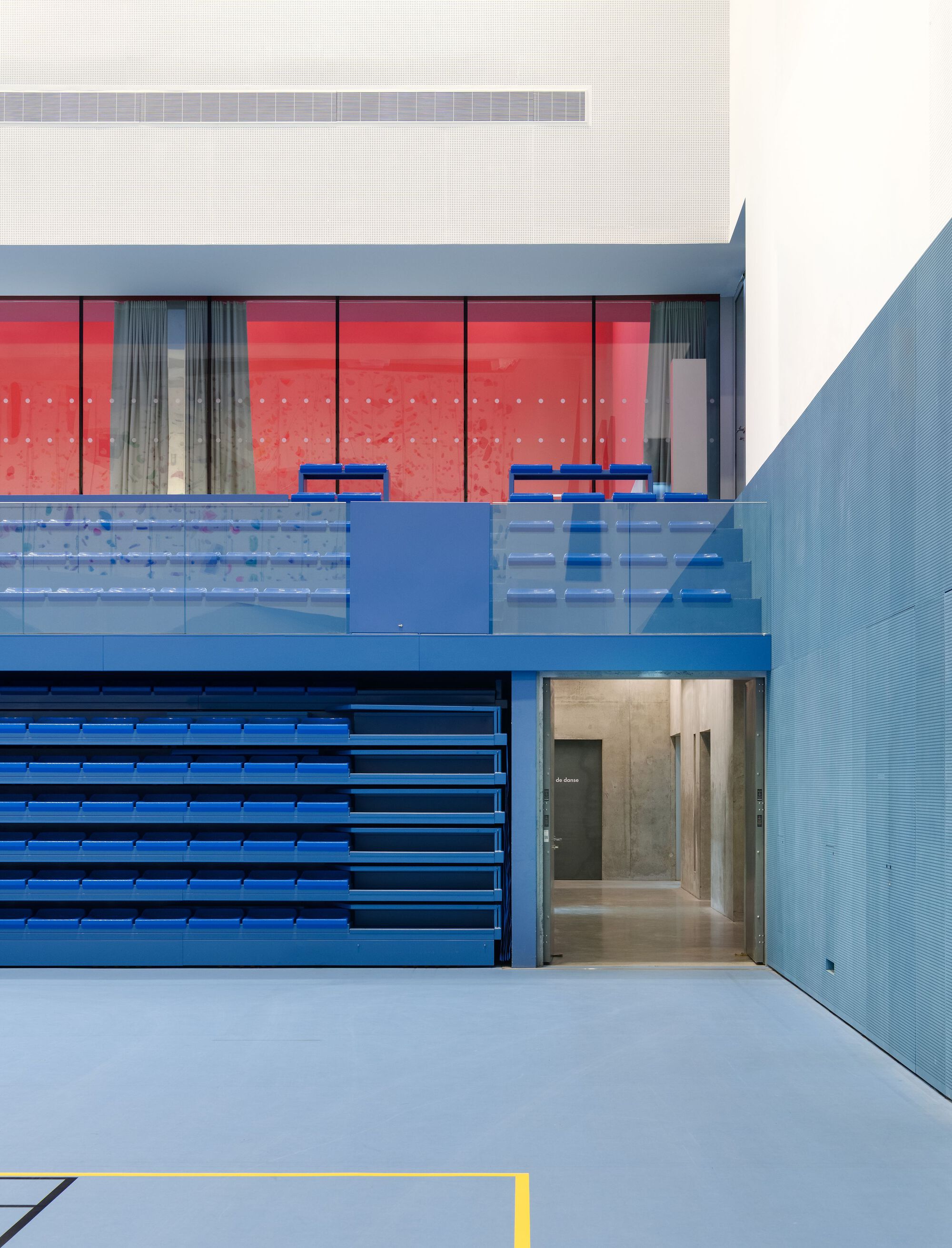 Courtyard facade showing blue metal bleachers, red tiled interior wall and glazed upper level