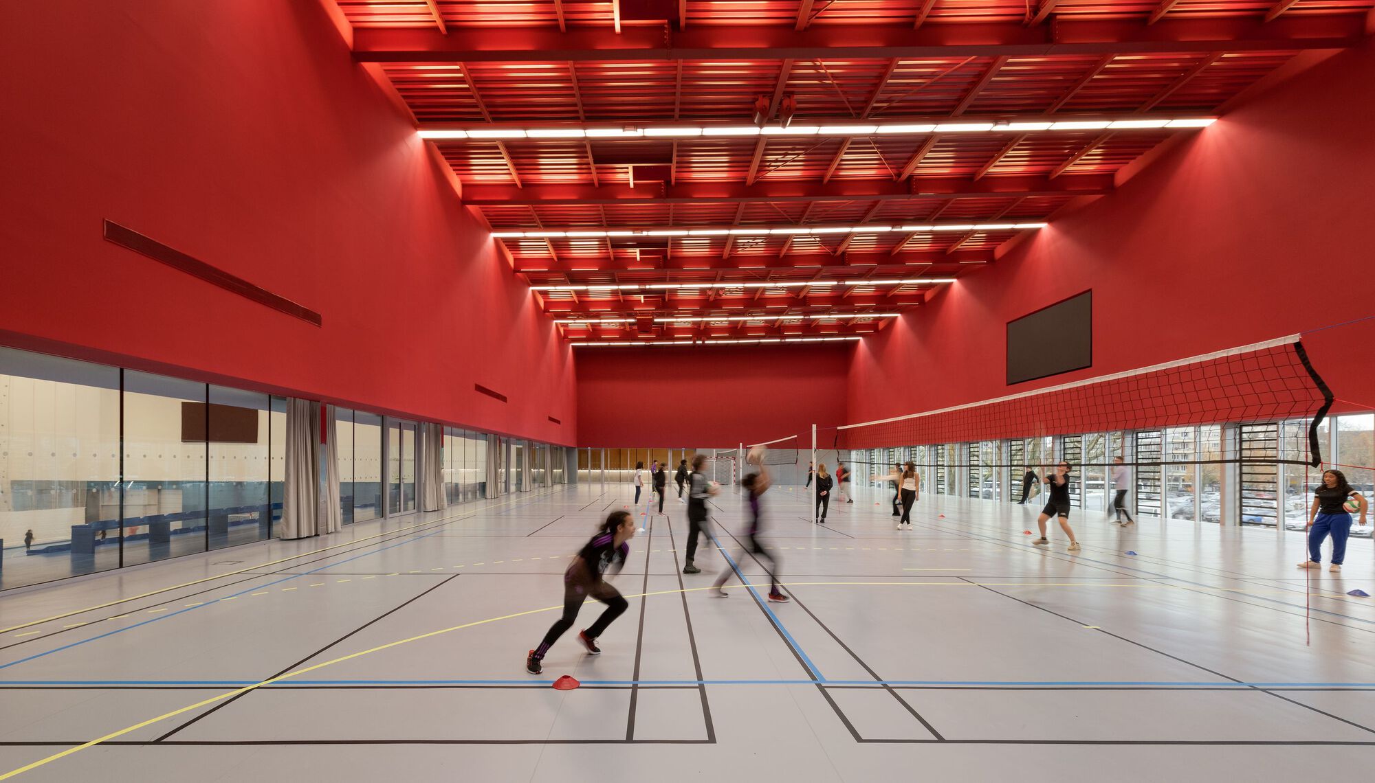 Players training on marked court beneath red suspended ceiling with recessed lighting