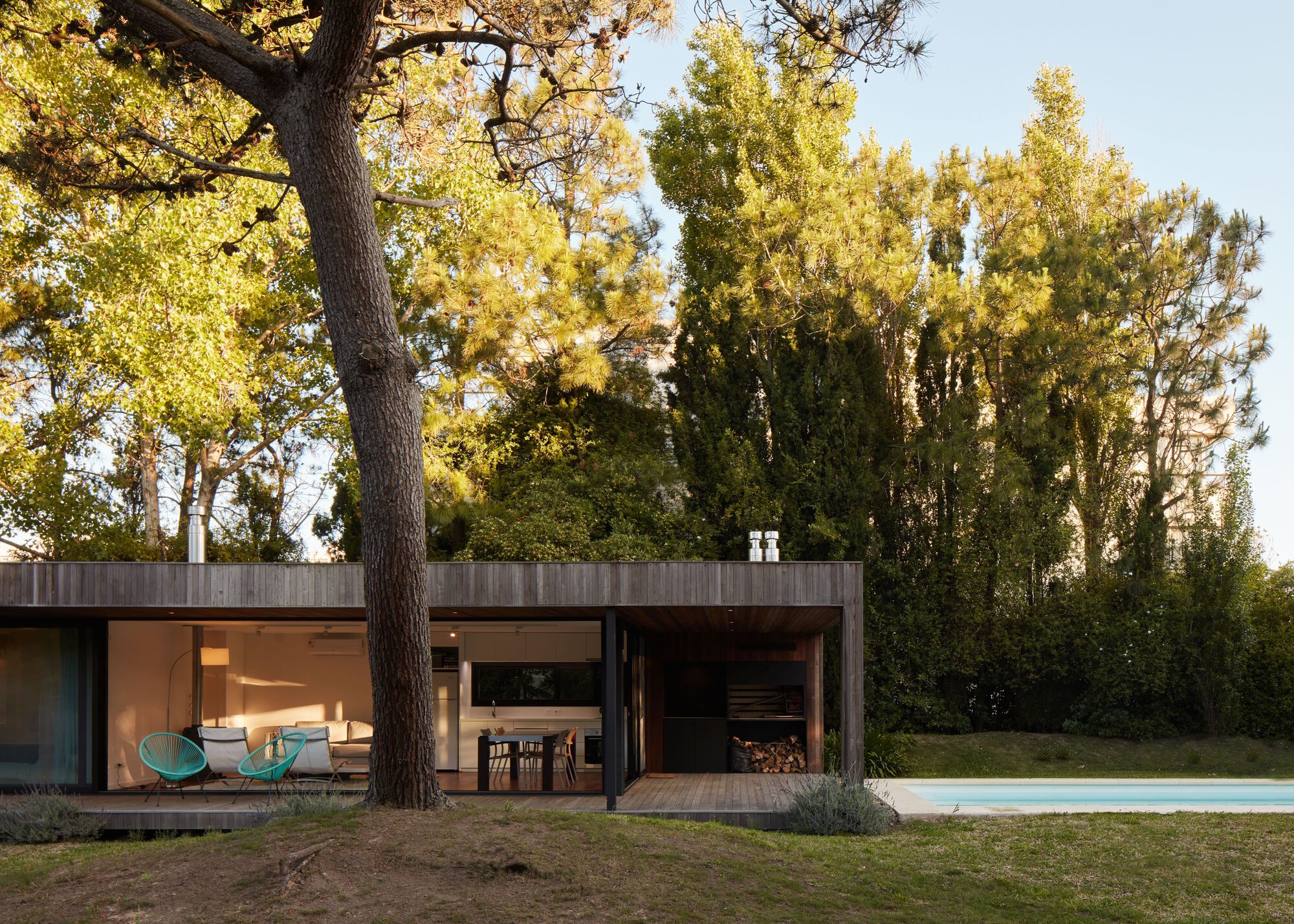 Garden facade with full-height glazing and firewood storage alcove at dusk