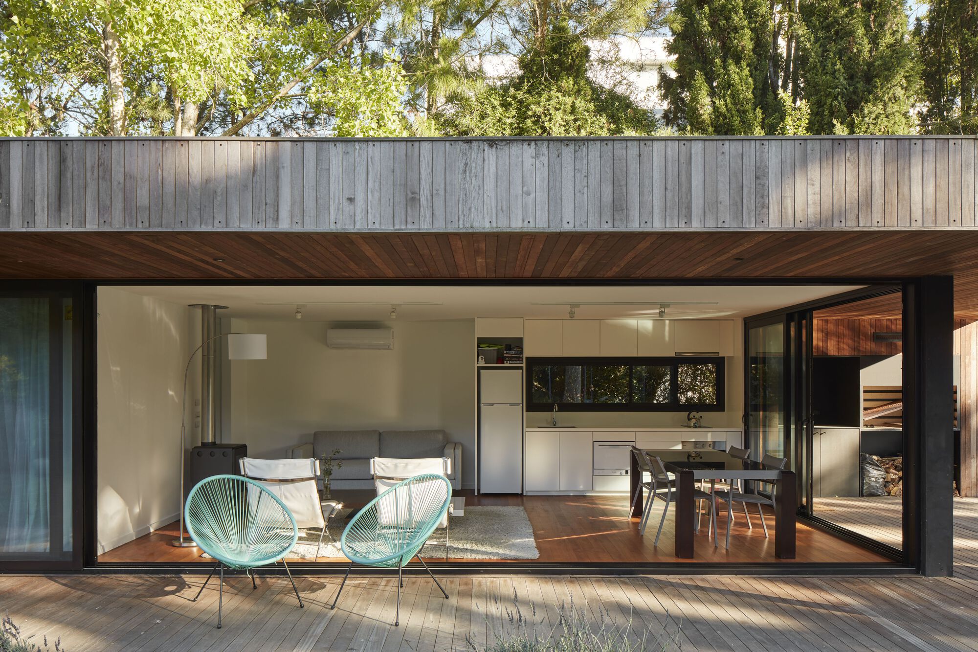 Open-plan living space with timber deck terrace and diagonal wood ceiling detail