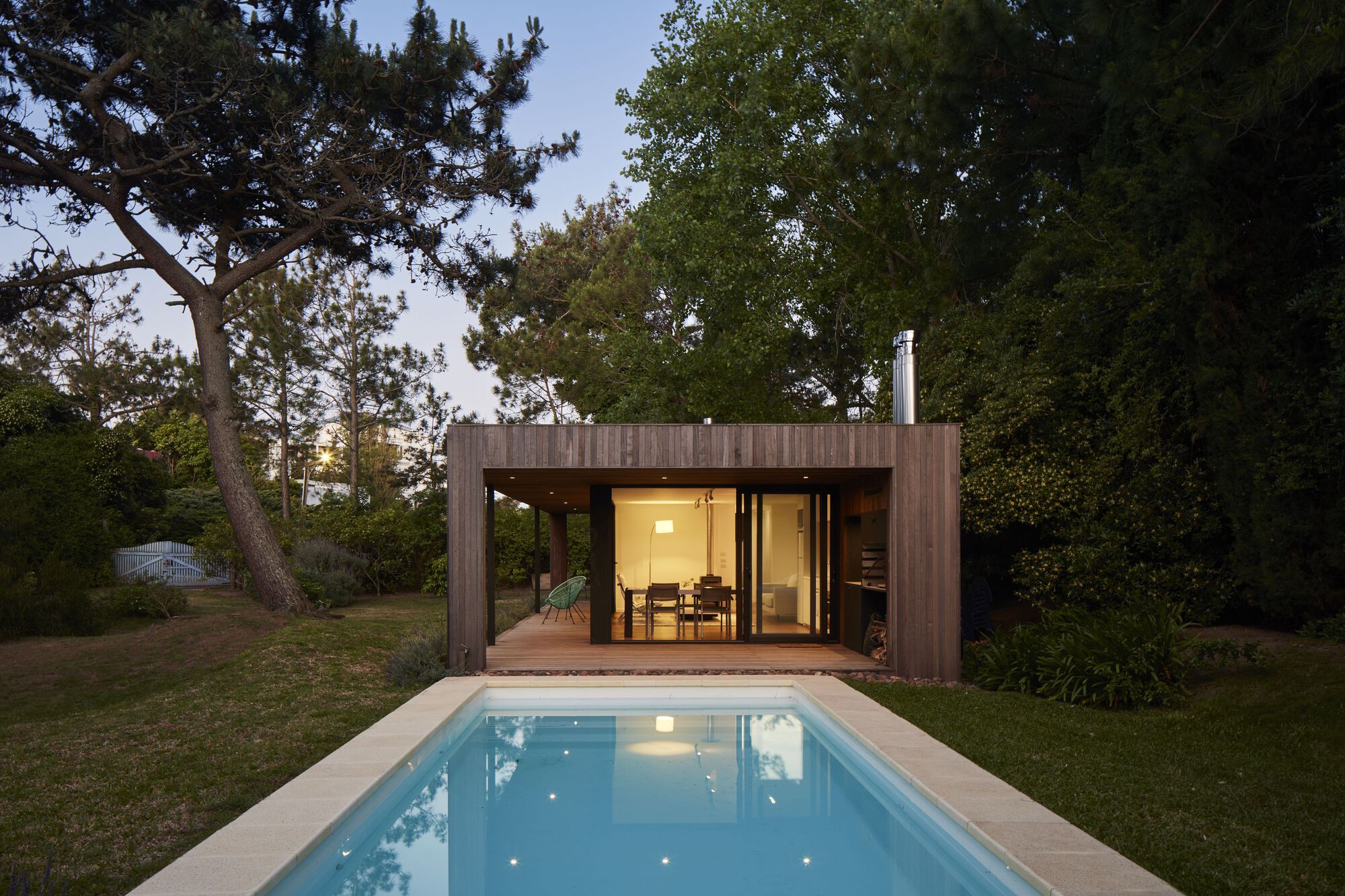 Rear elevation with illuminated interior and reflecting pool at twilight