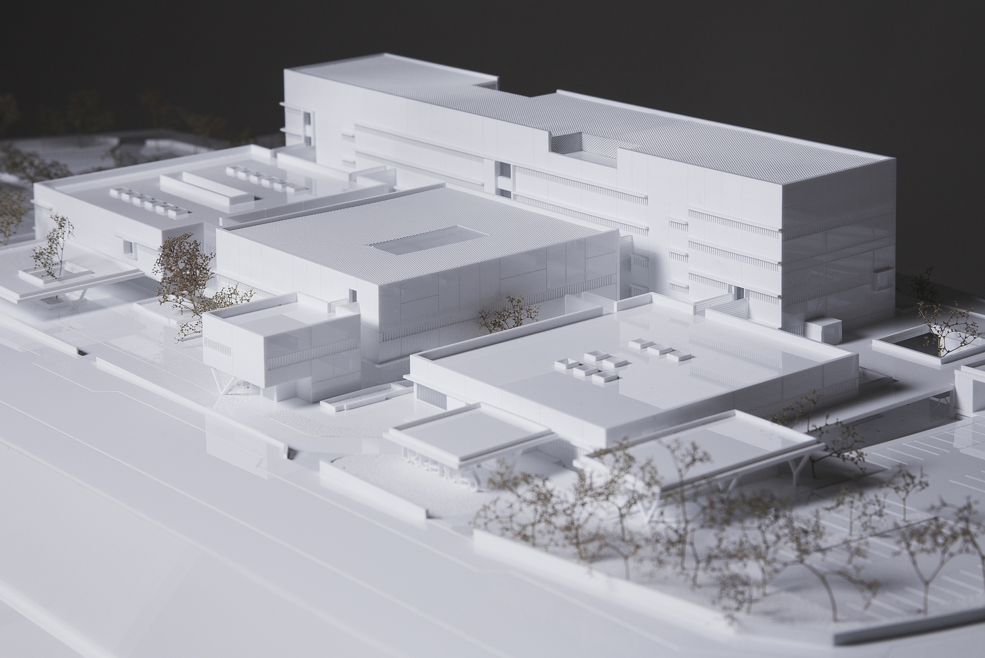 Physical model showing white massing with flat roofs, internal courtyards and miniature trees
