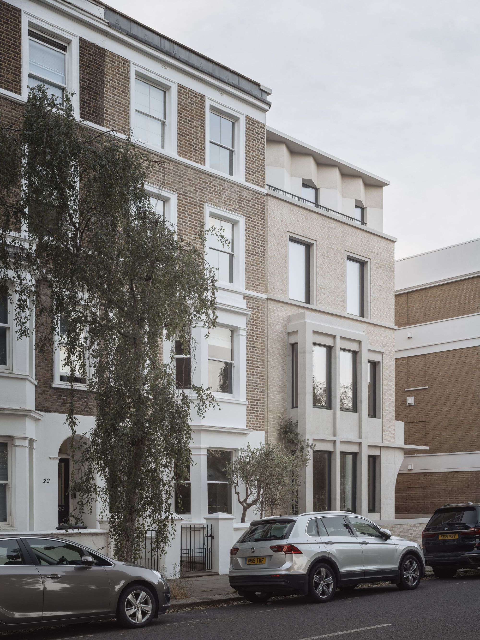 Street view of the four-storey brick facade with a mature tree growing at the entrance