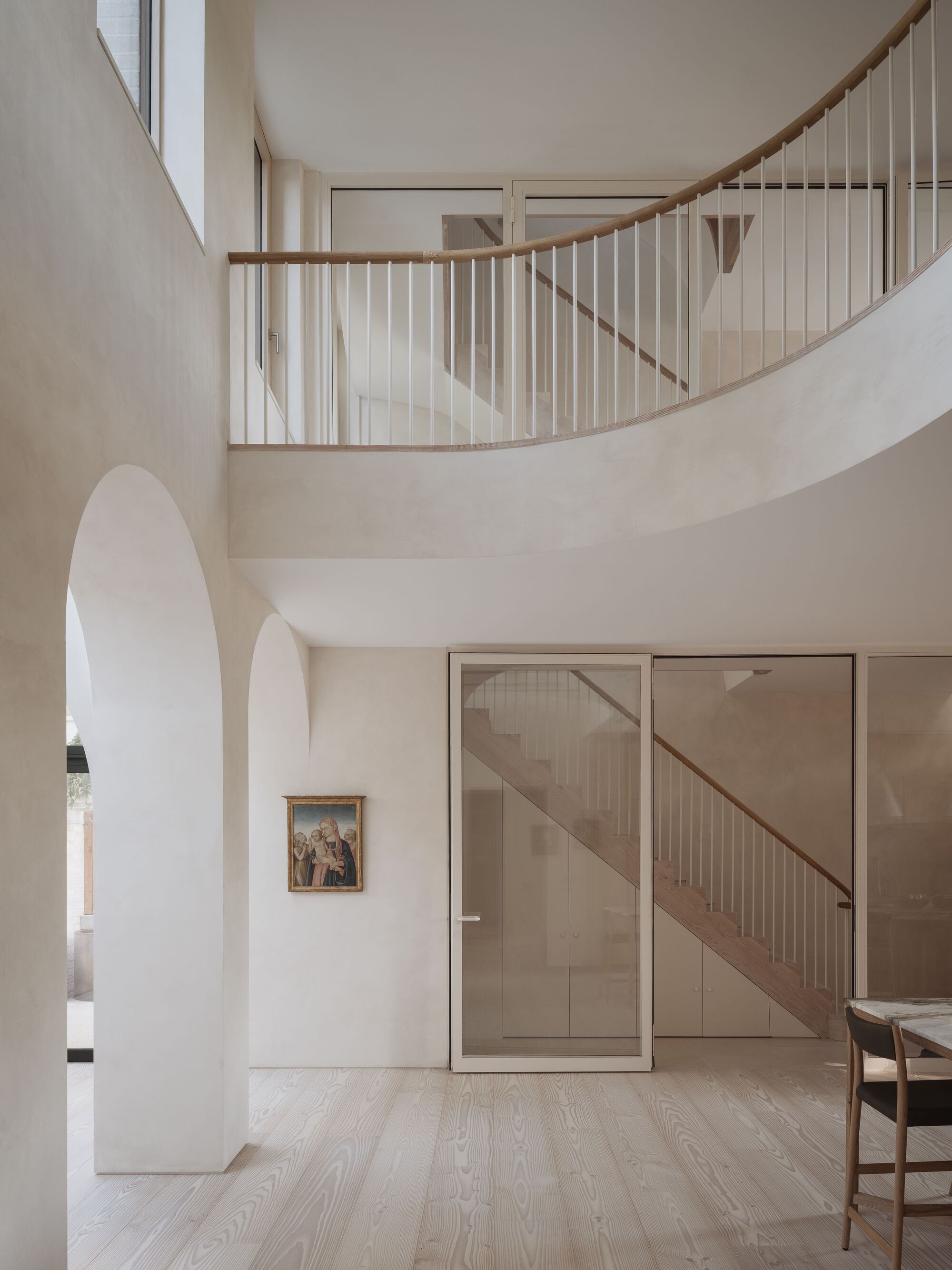 Double-height entrance hall with curved staircase, vertical balustrade and pale timber flooring