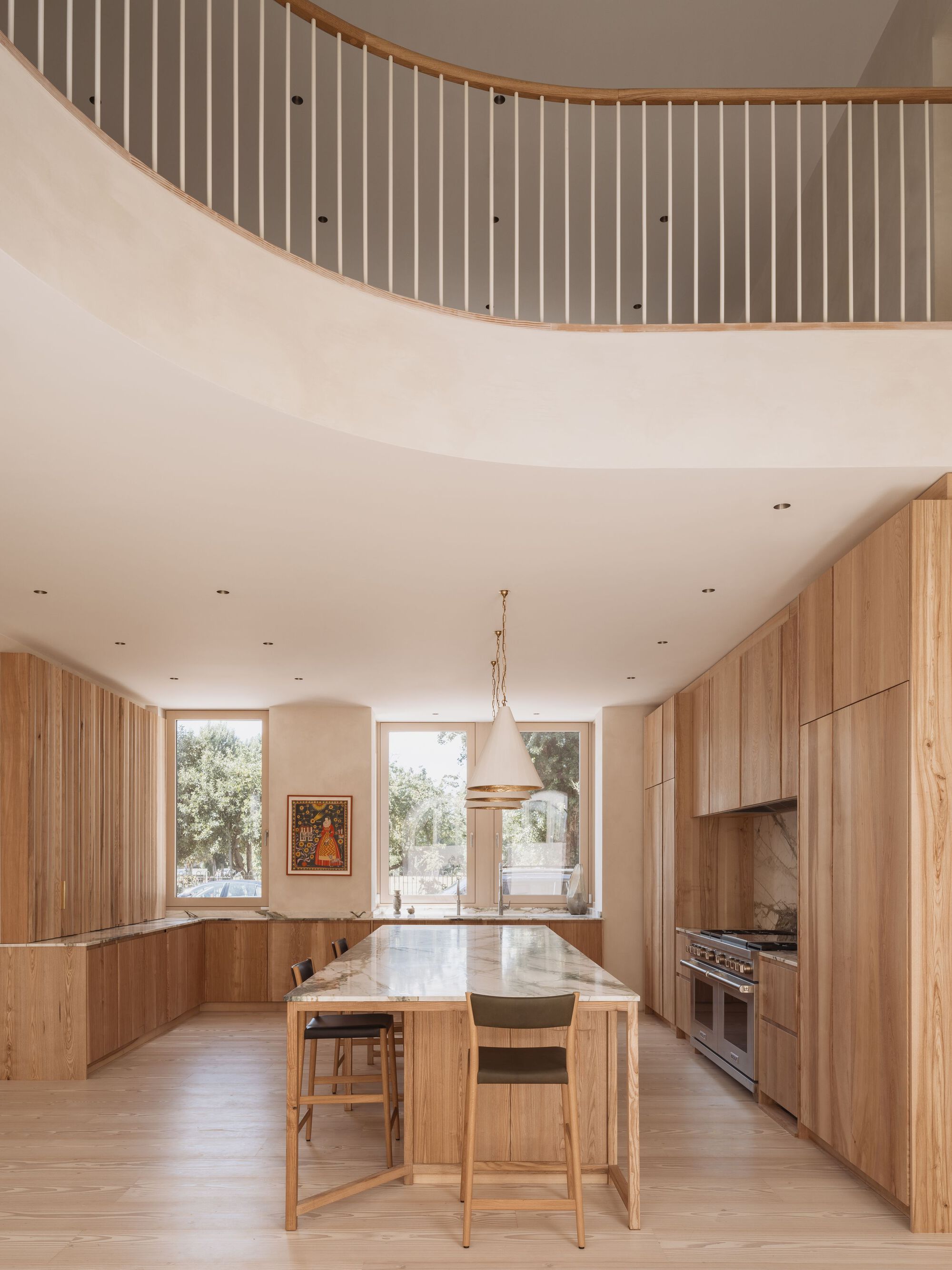 Kitchen with timber cabinetry and island beneath the curved stairwell balustrade above
