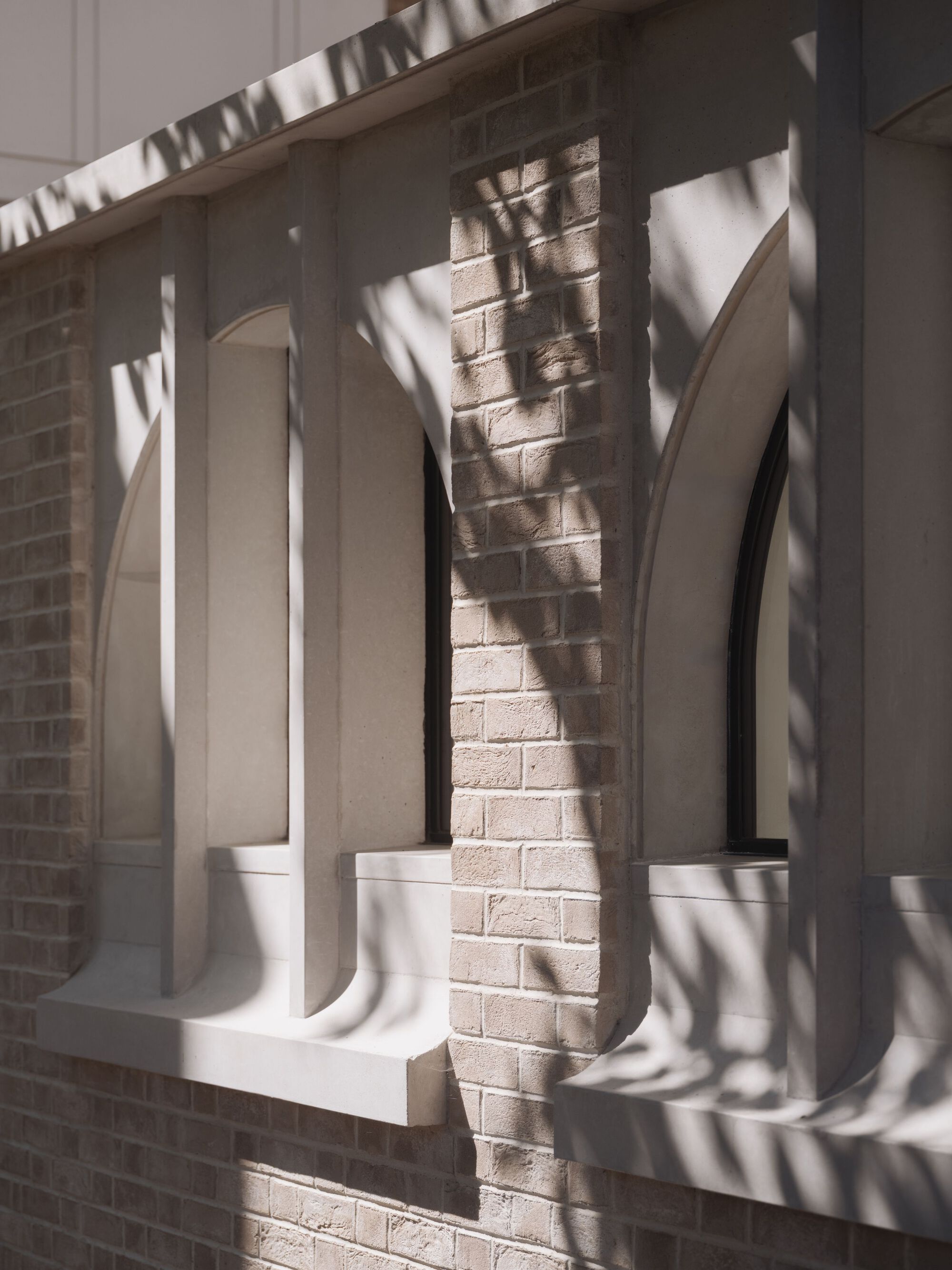 Close-up of the white balustrade casting sharp shadows on pale brick beneath afternoon sun