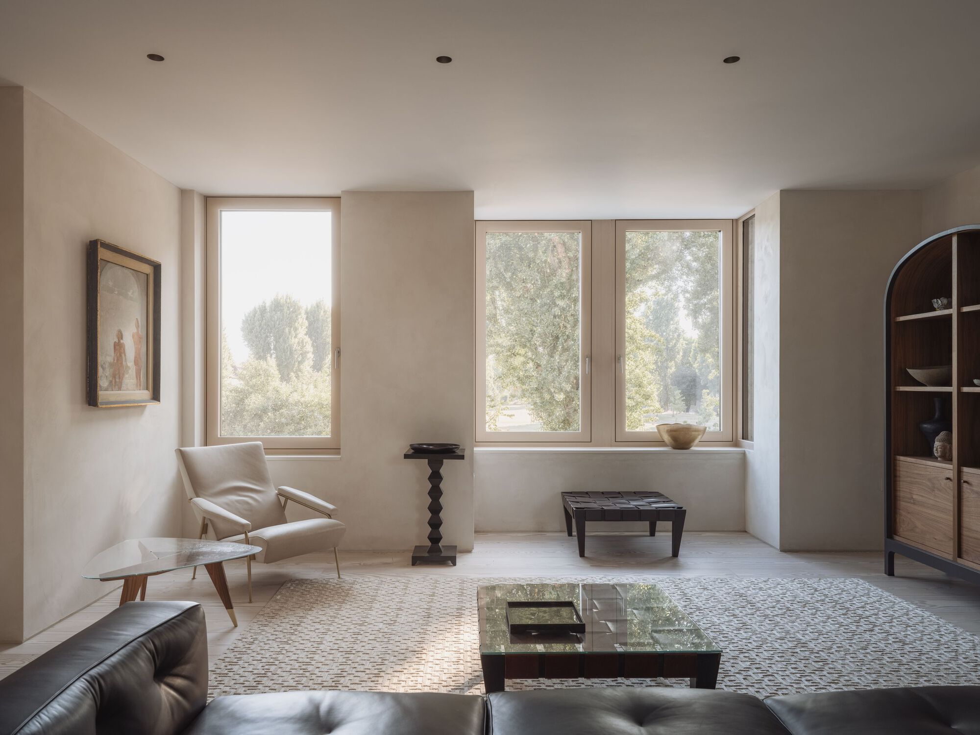 Living room with three large windows overlooking misty trees and a pebble mosaic floor