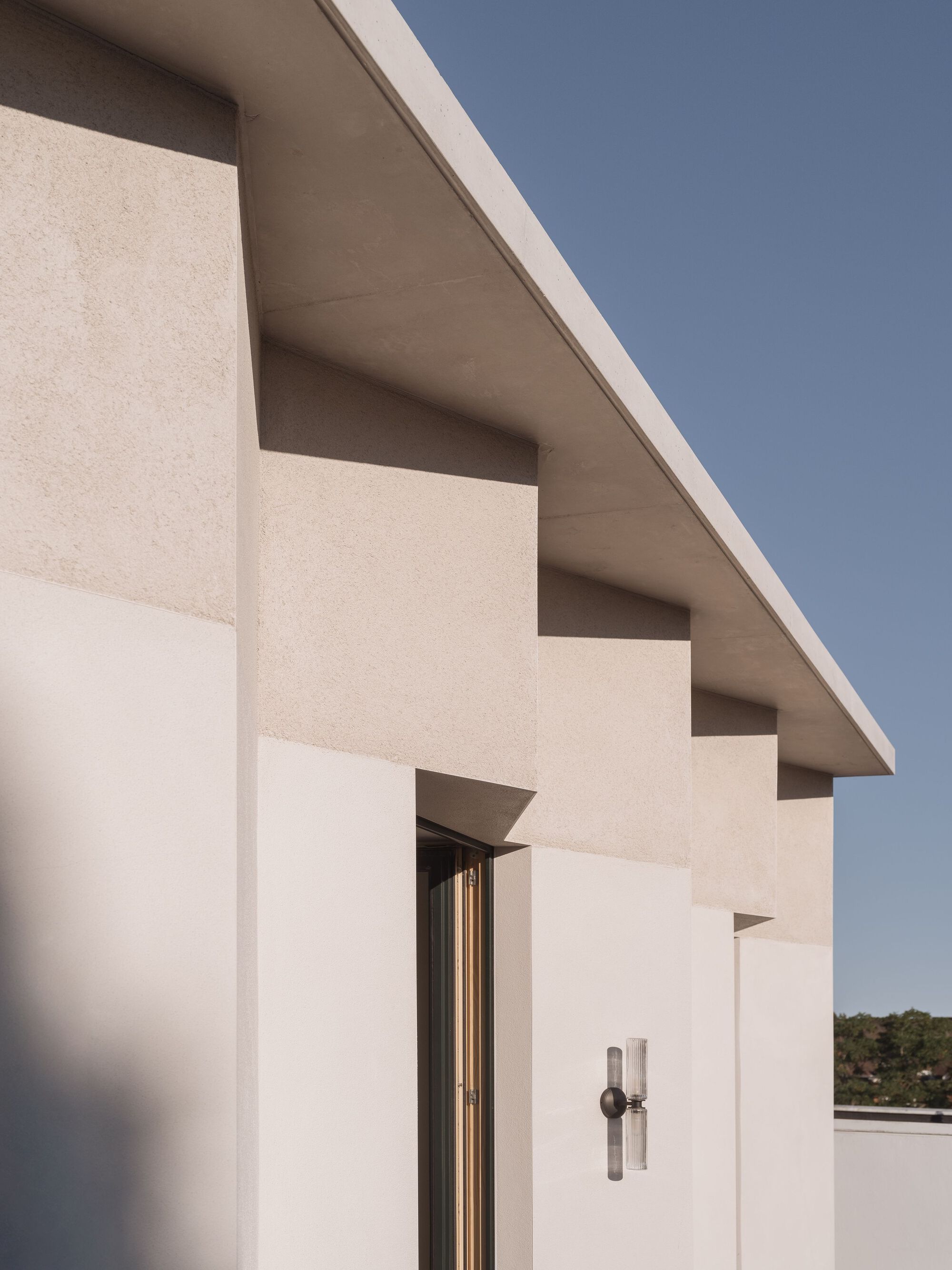 Stepped roofline with deep eaves and pale stucco walls beneath a cloudless sky