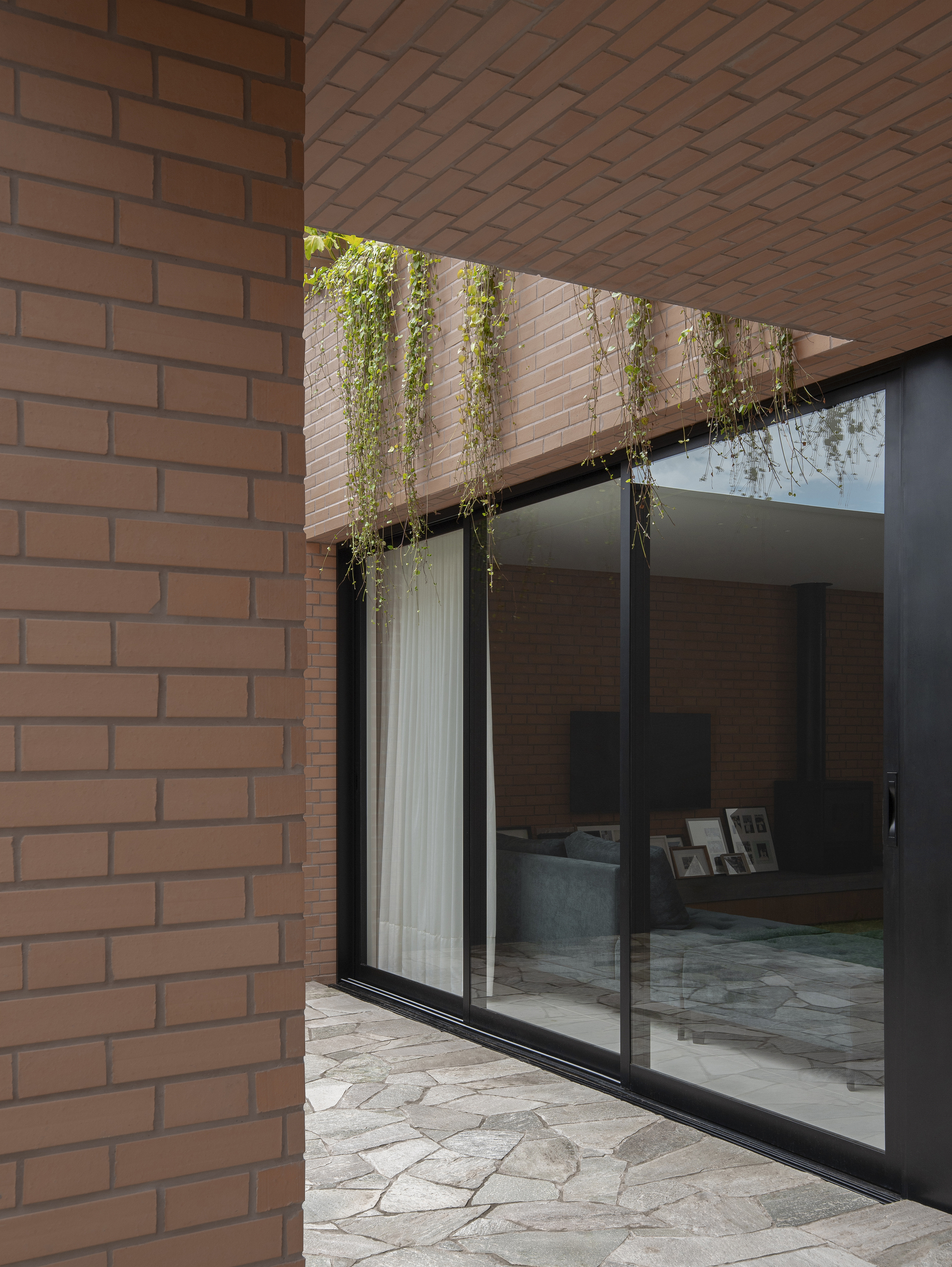 Sliding glass door opening to courtyard beneath a planted balcony with trailing greenery