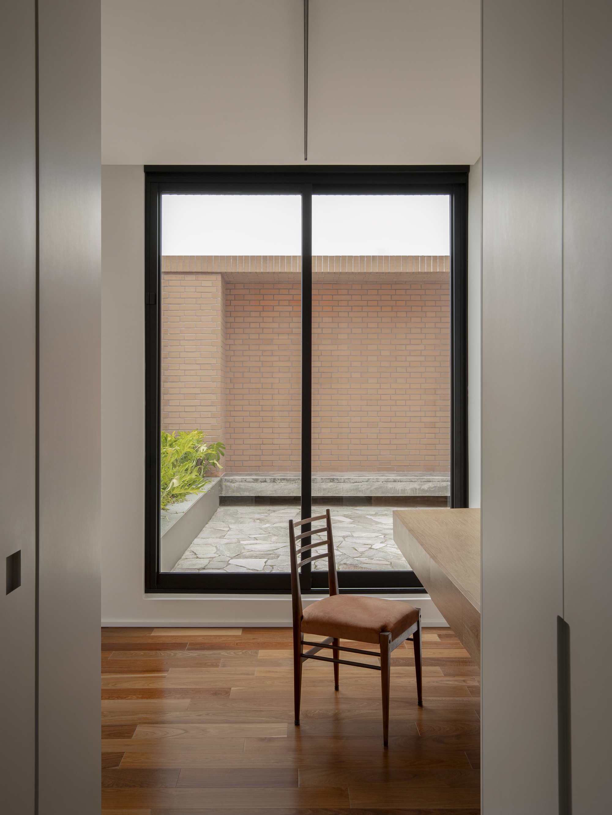 Interior workspace with timber desk and single chair framed by white walls and black window