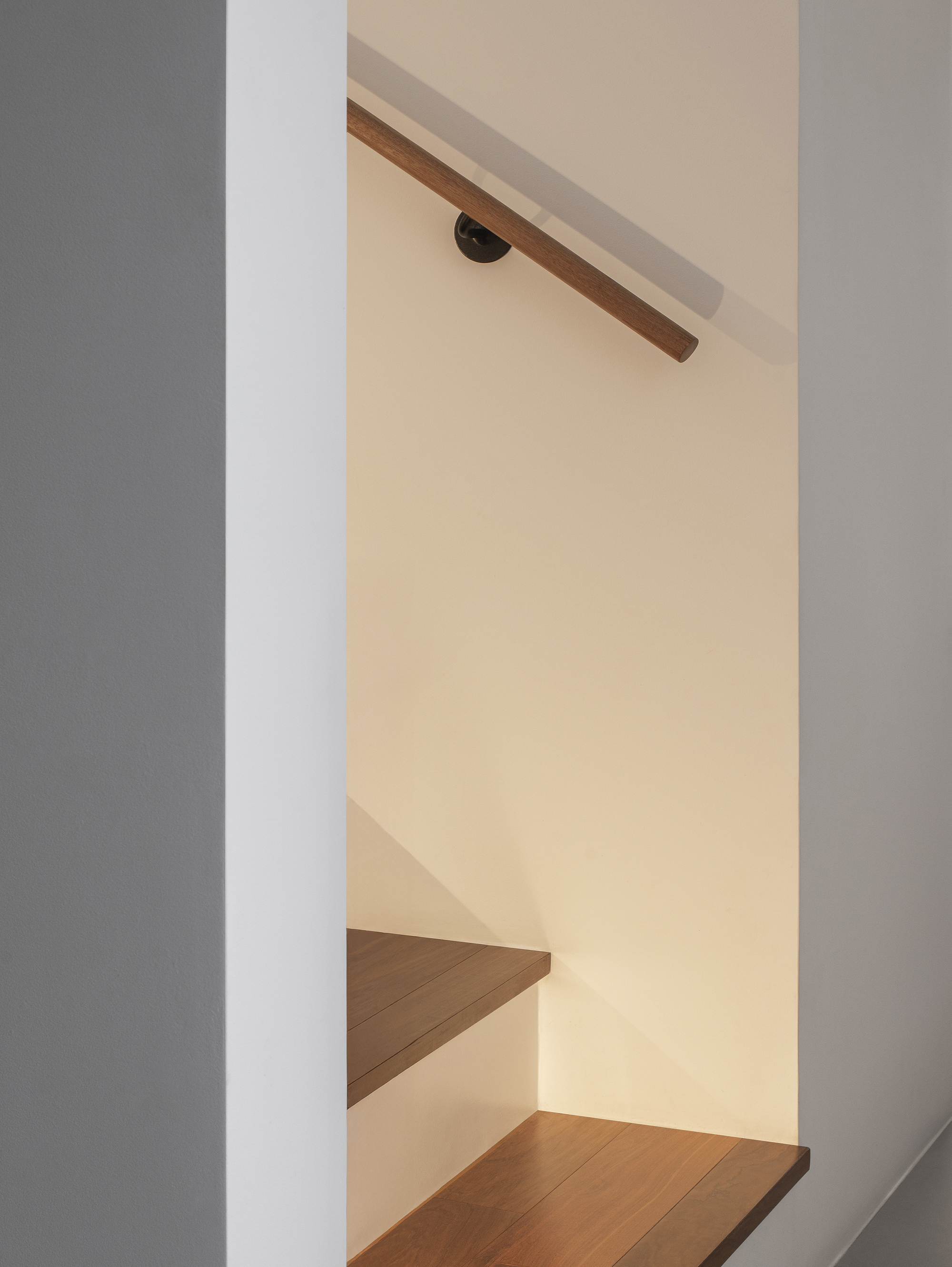 Detail of timber handrail meeting wall bracket beneath warm ambient lighting