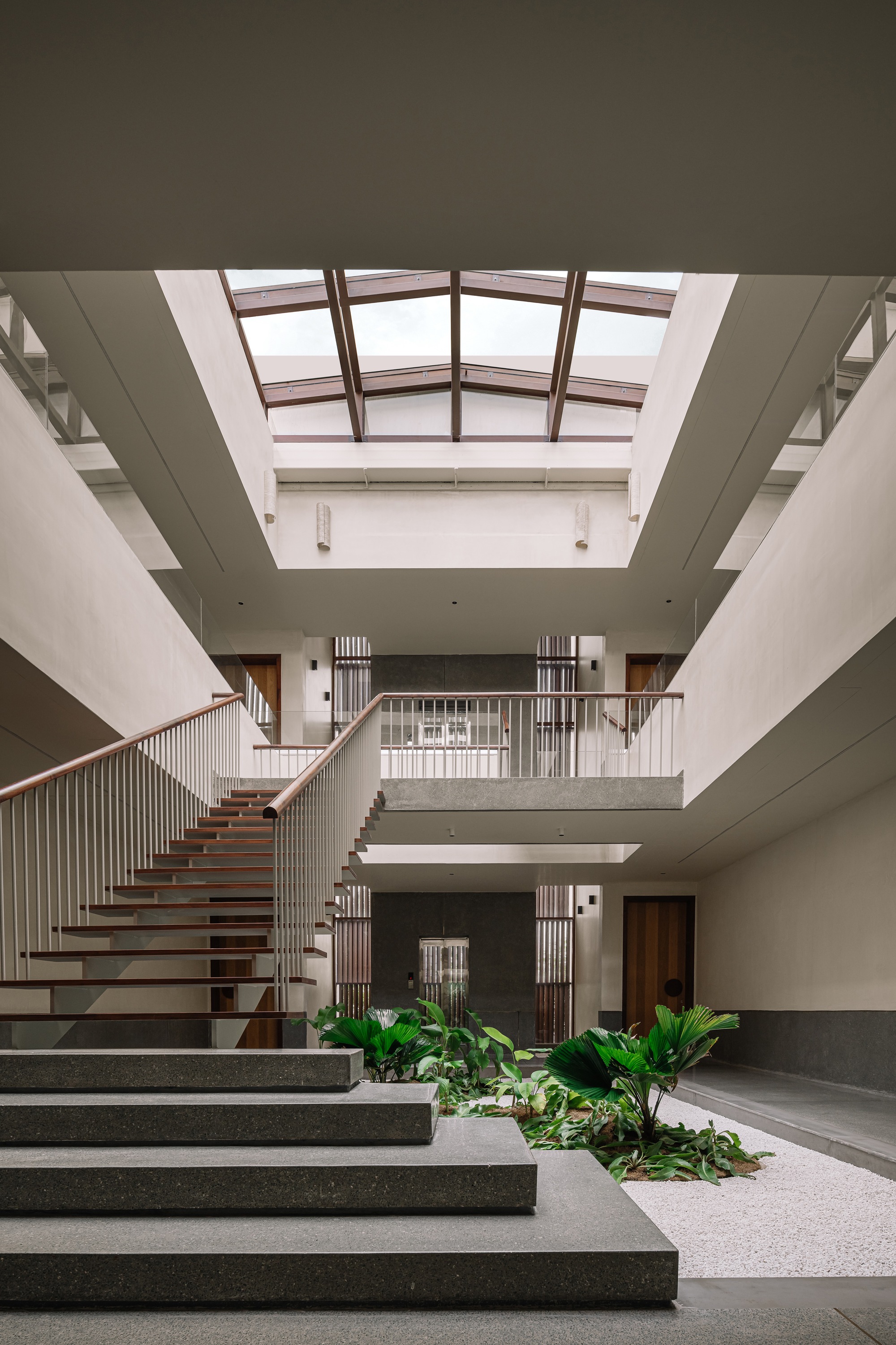 Triple-height entry hall with floating staircase and clerestory skylight above planted courtyard beds