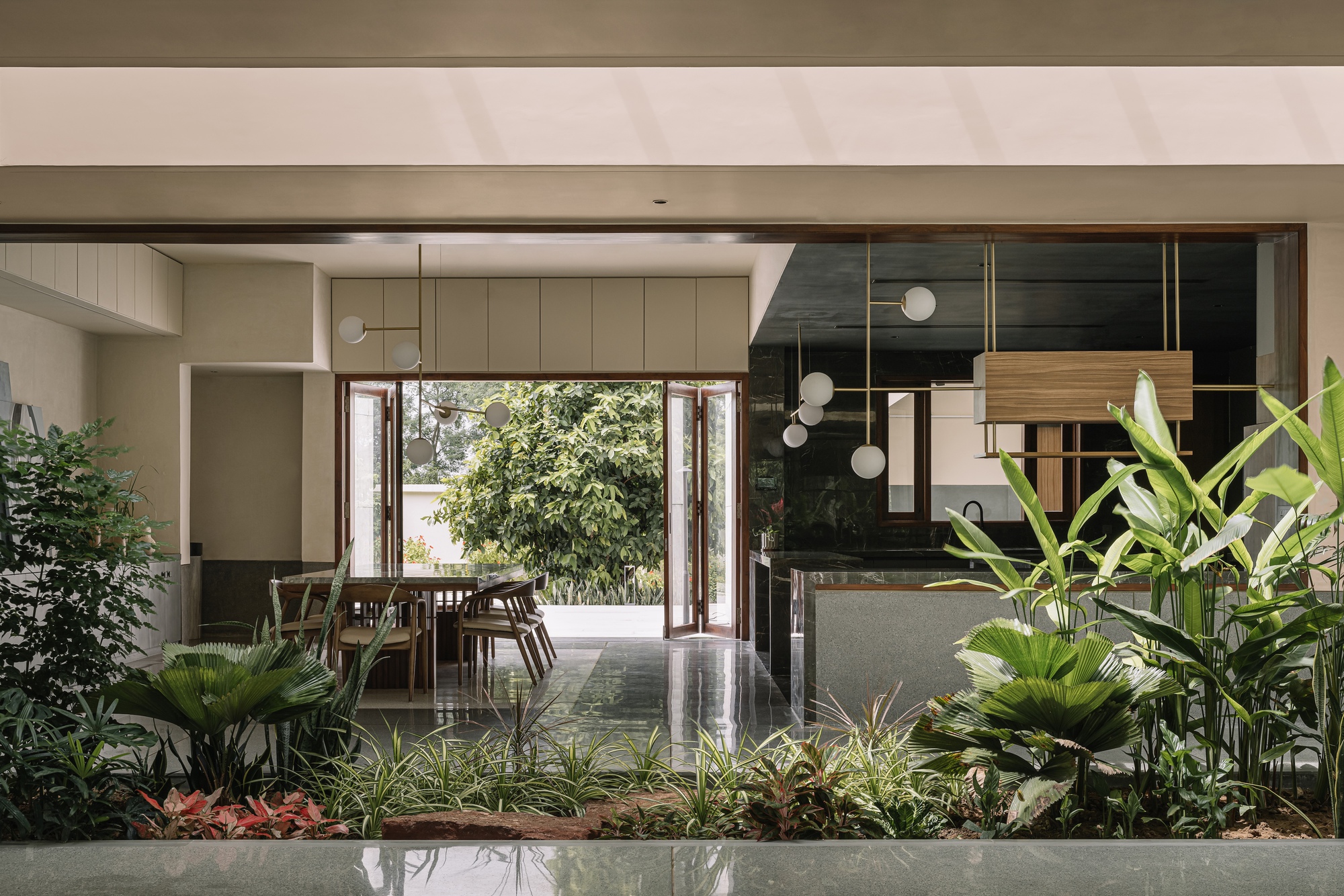 Interior view through planted bed toward open-plan kitchen and dining area with double doors to courtyard