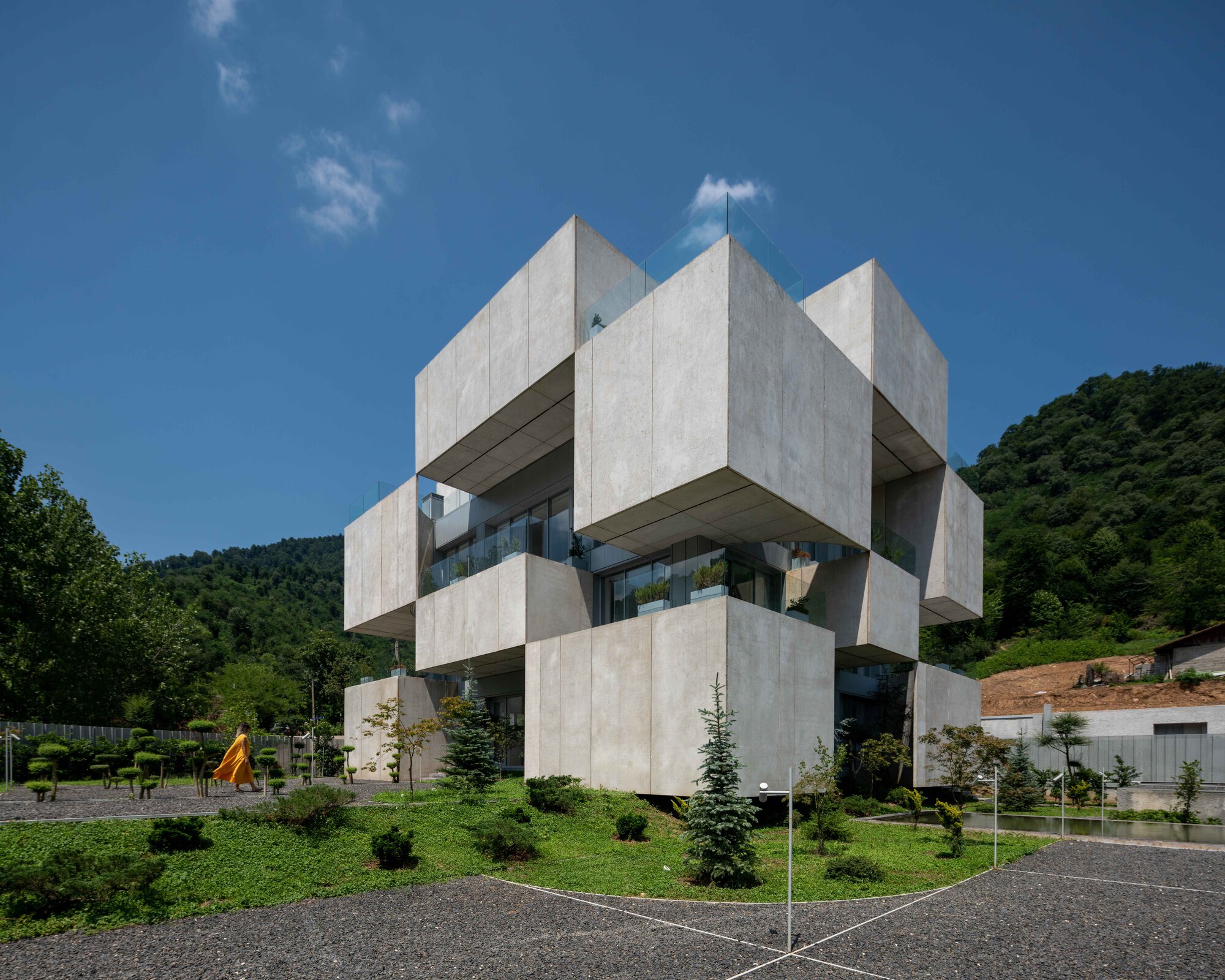 Corner view of the concrete facade showing interlocking cubic forms with recessed glazing under blue sky