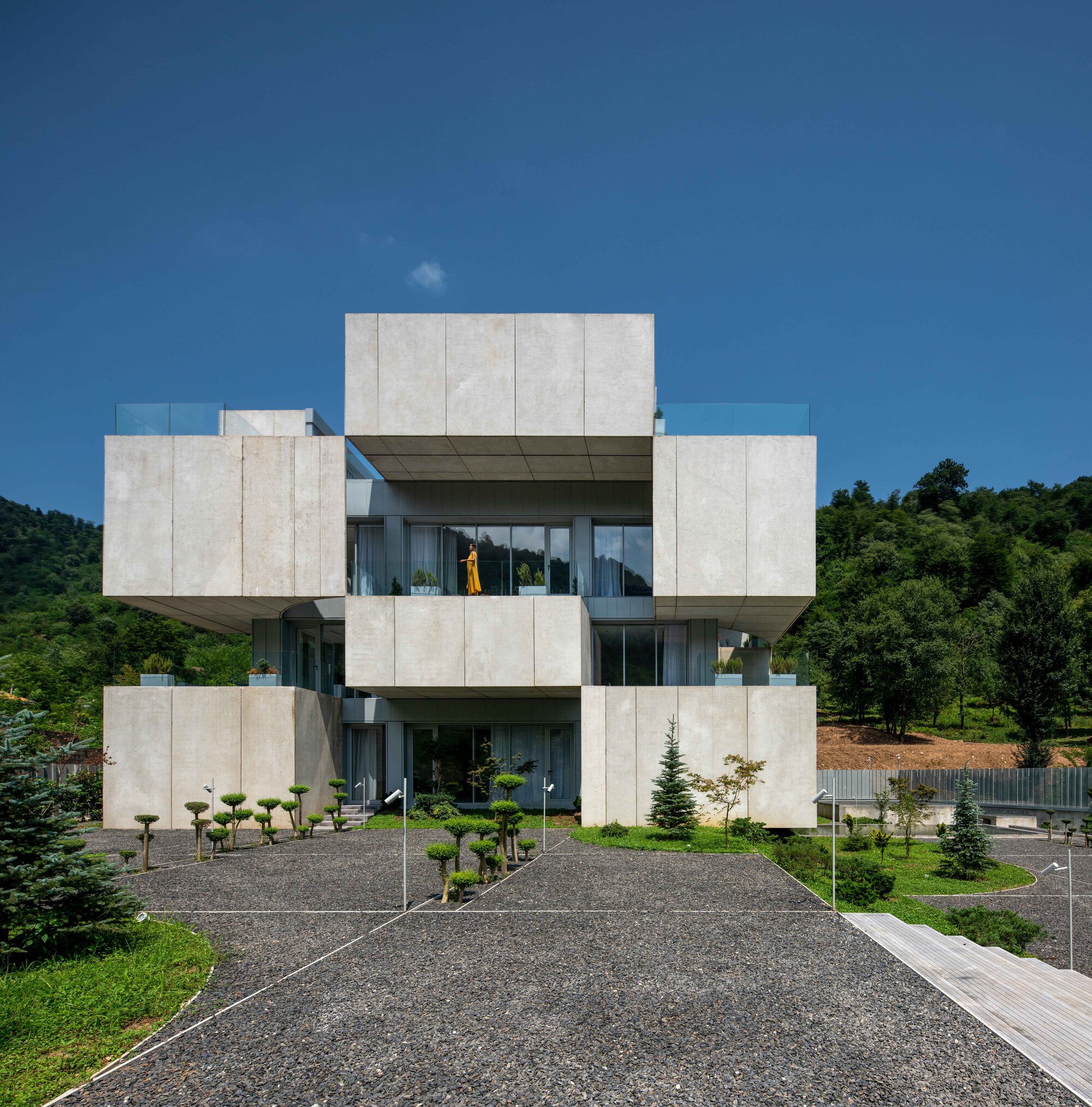 Front elevation showing the symmetrical concrete facade with projecting balconies and gravel approach path
