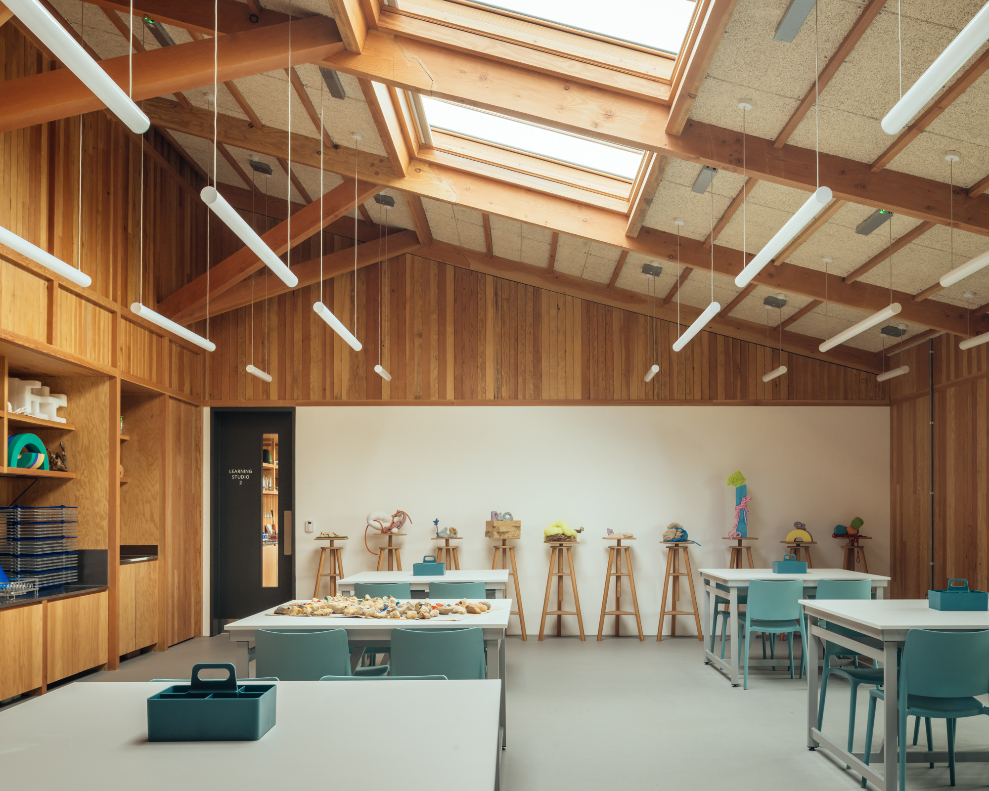 Workshop space with cork ceiling panels, timber framing and wooden easels arranged along a whiteboard wall
