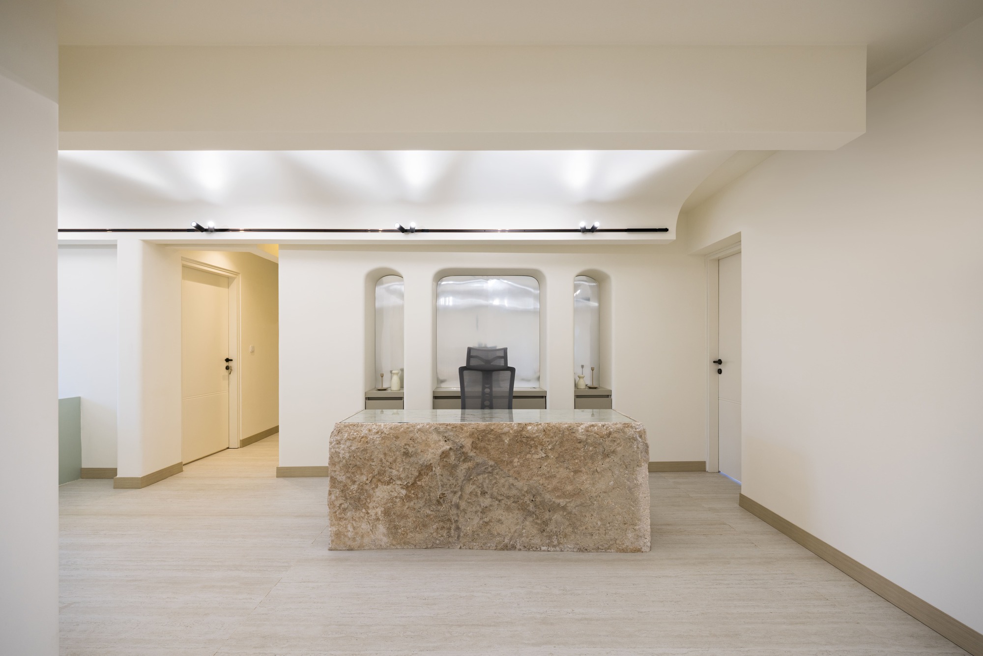 Lobby space with freestanding stone reception desk and arched openings framing symmetrical archways beyond