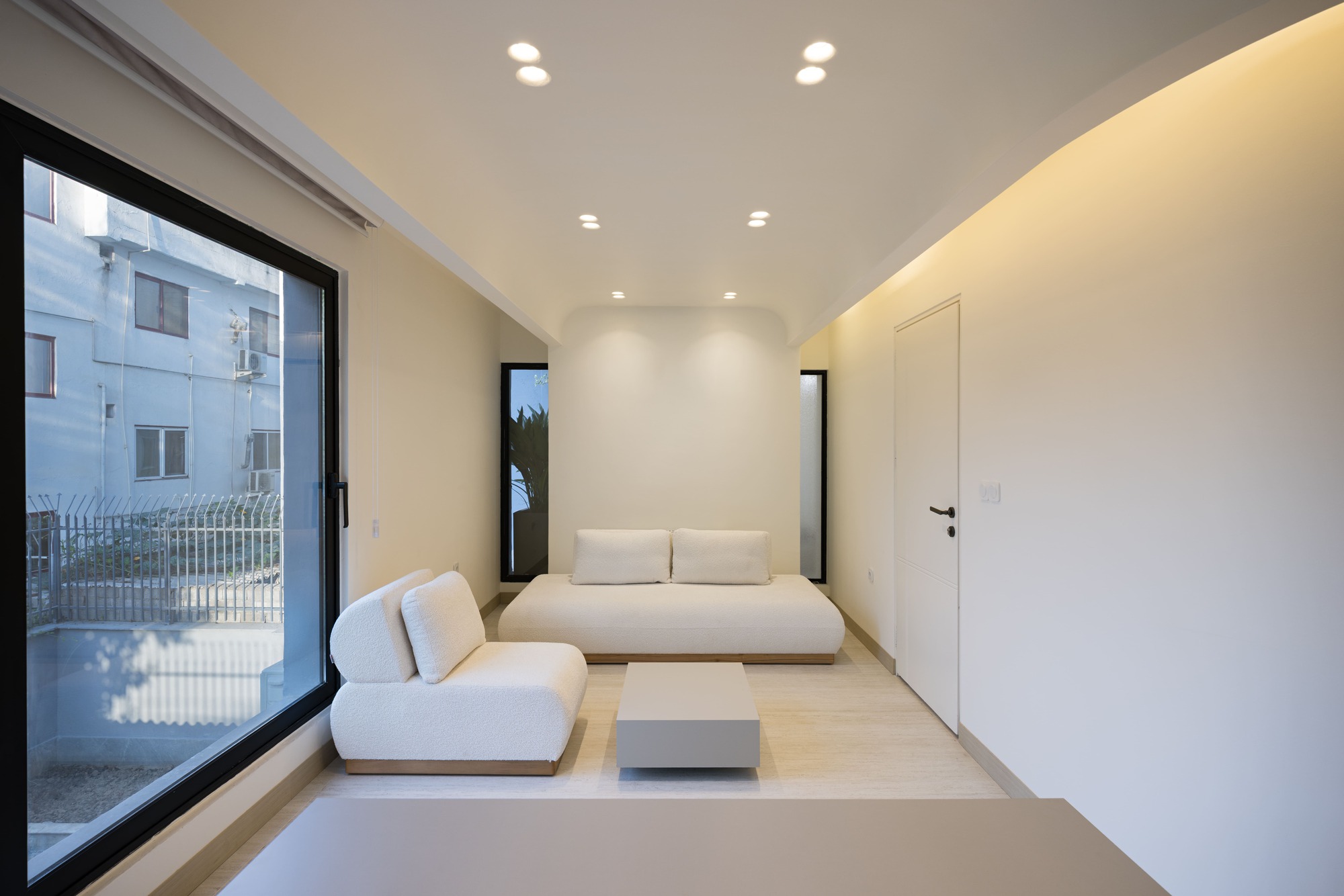 Minimalist living area with large sliding glass door and narrow vertical window in white walls