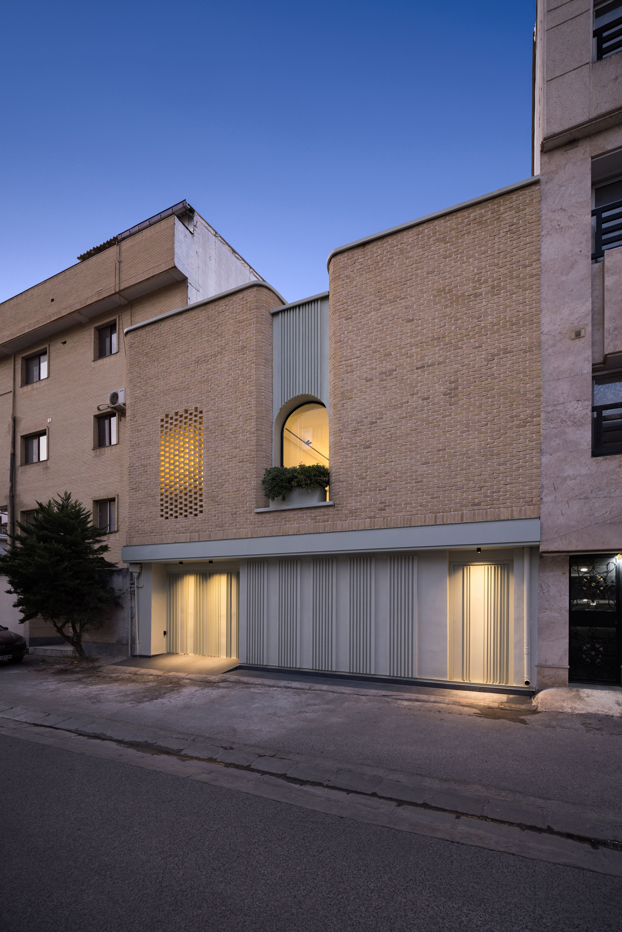 Street view of the two-story brick facade with corrugated metal garage door at twilight