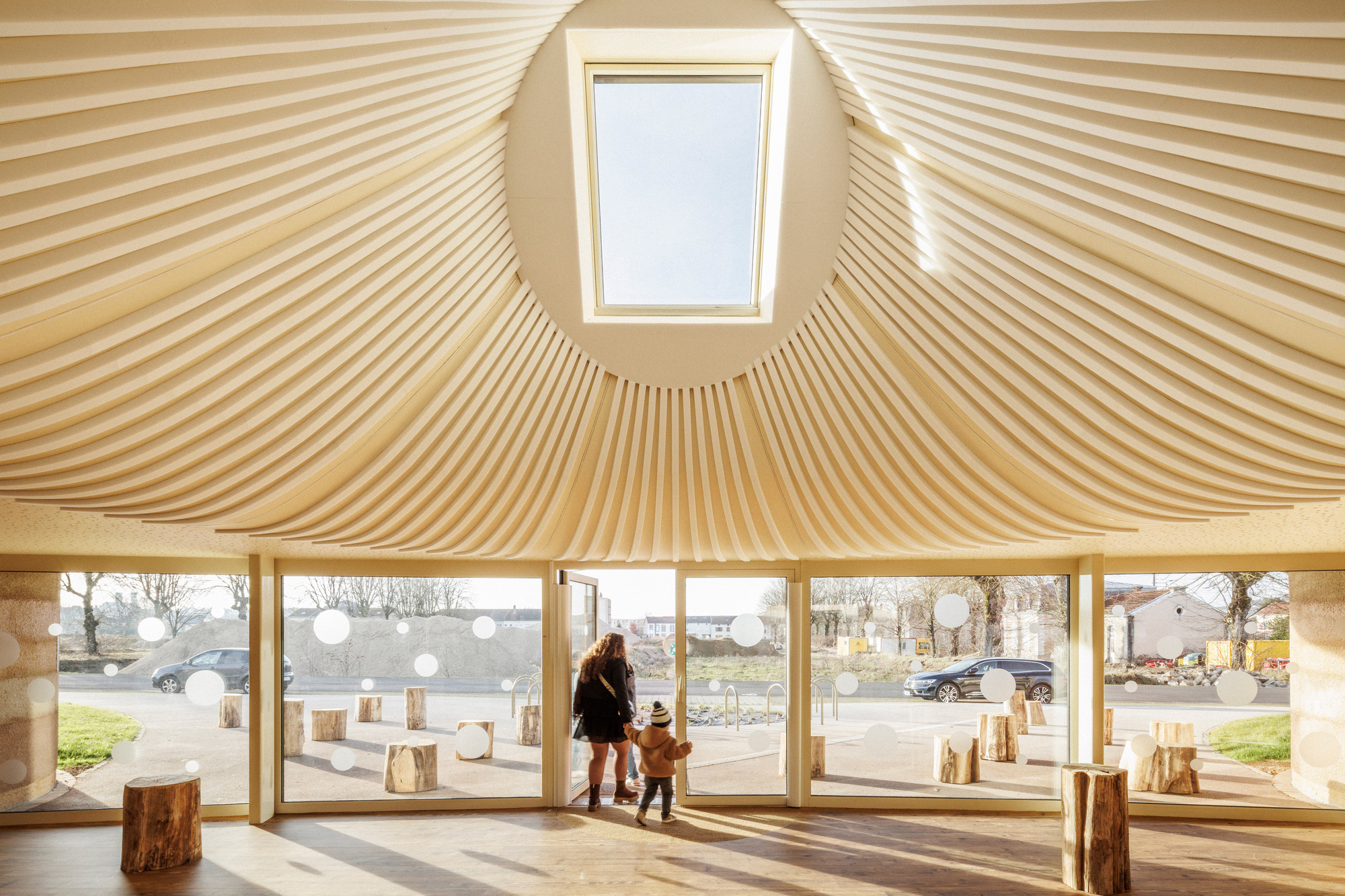 Interior view of the radial timber ceiling with skylight above and a parent with child near the glazed perimeter