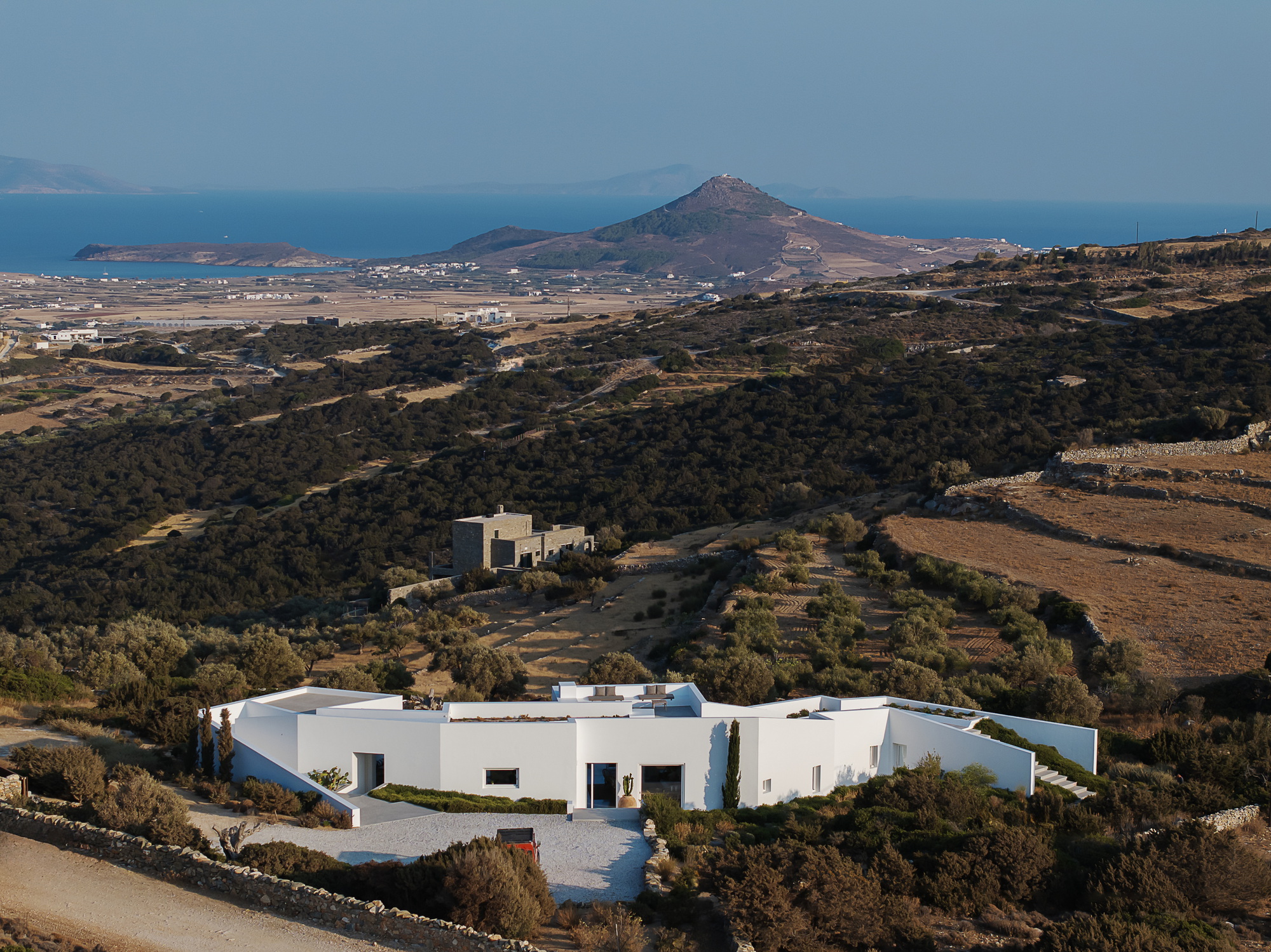 Aerial view of the white rendered residence among dry scrubland with coastal mountains in the distance