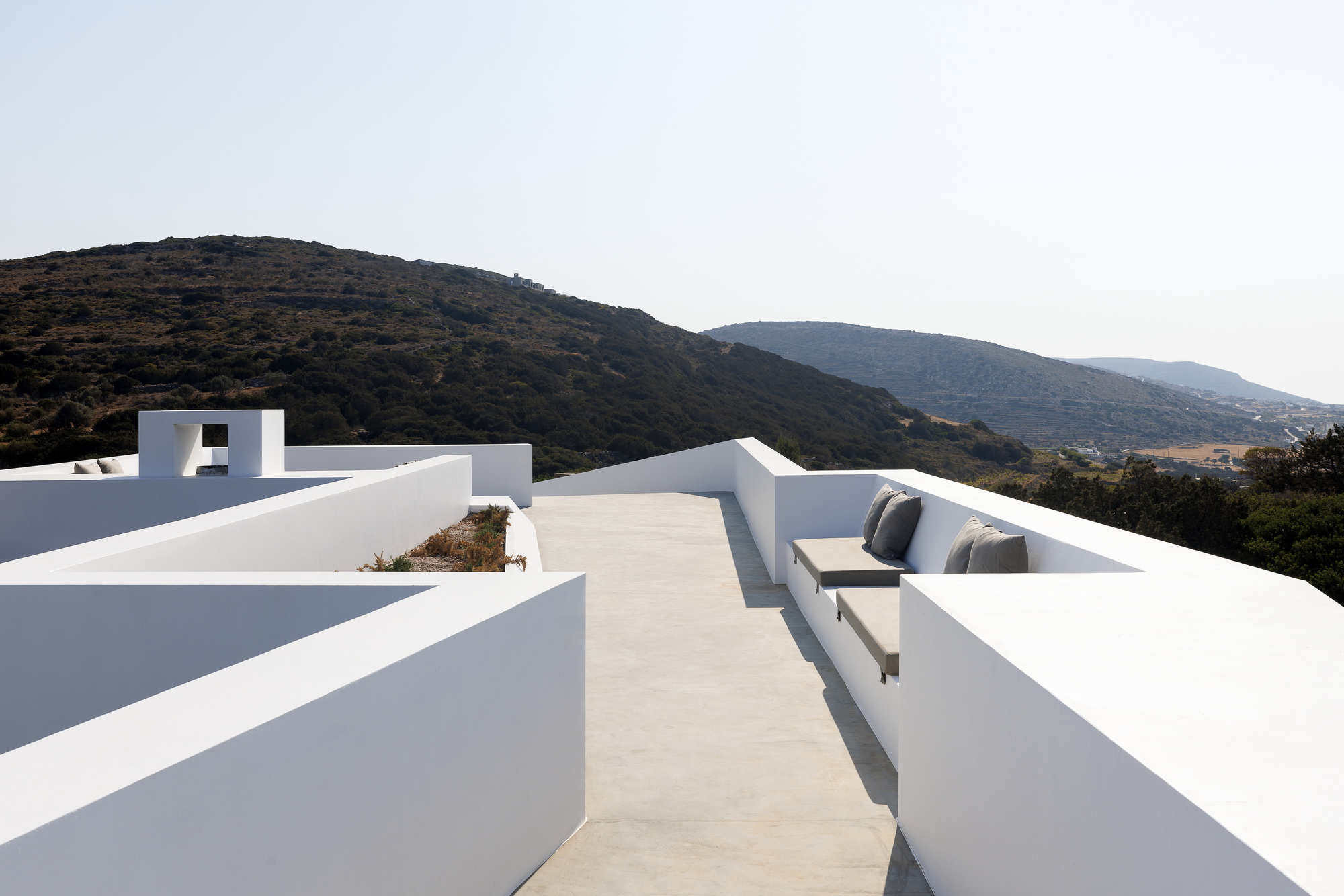 Rooftop terrace with white plastered parapets and built-in seating facing mountain ridgelines