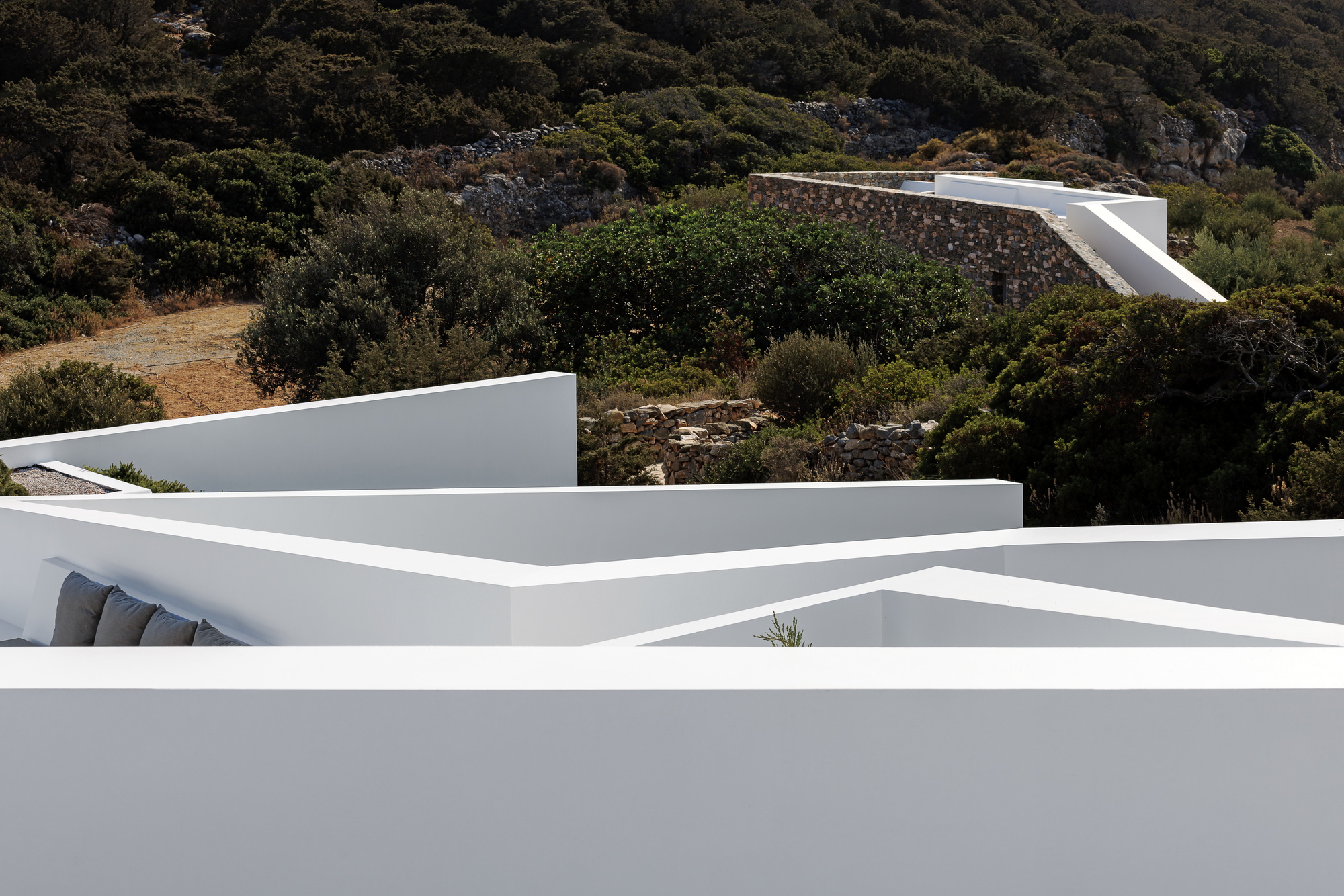 Overlapping white rooflines cascading down the hillside amid native vegetation