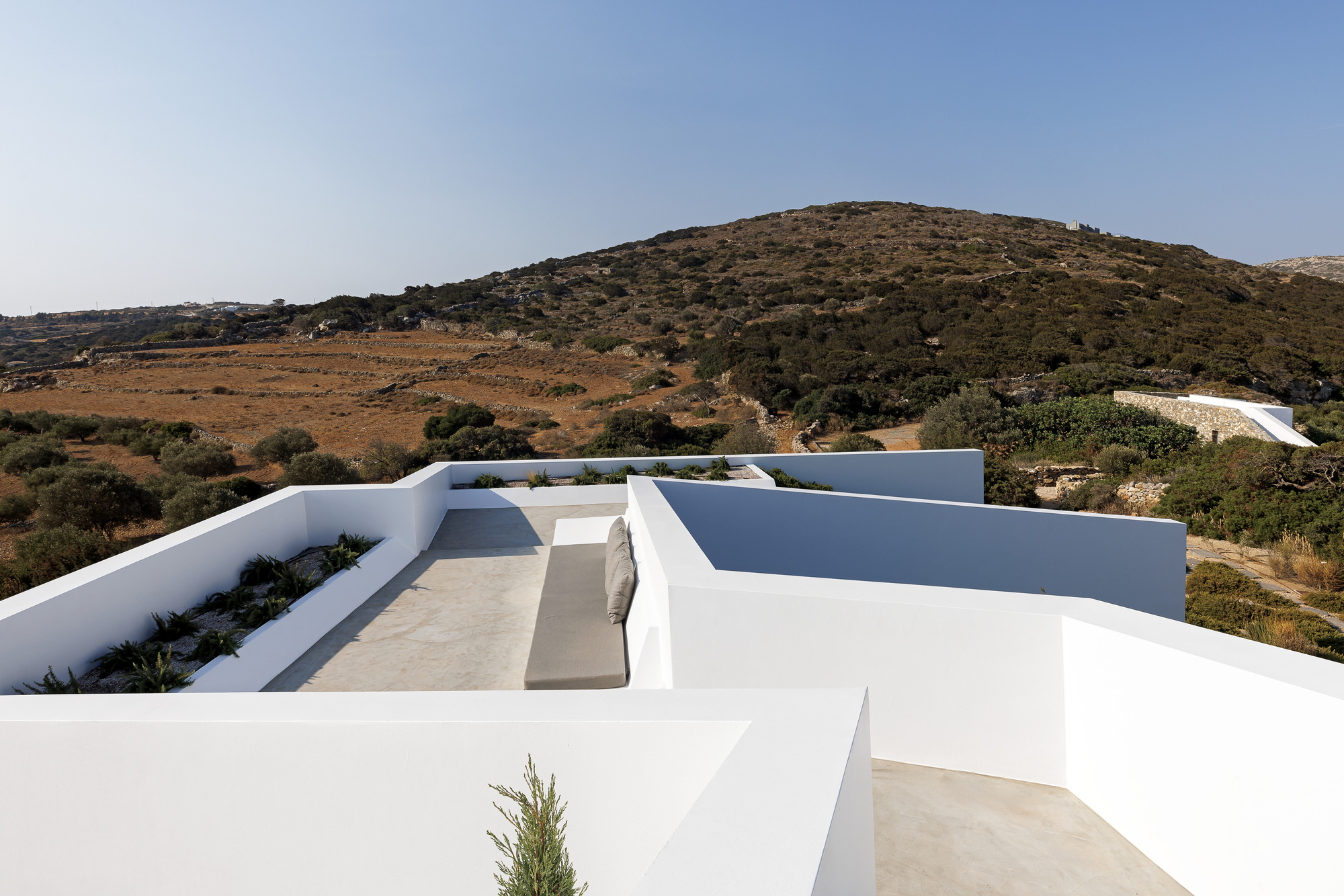 Rooftop terrace with curved planters and terraces set against a dry hillside