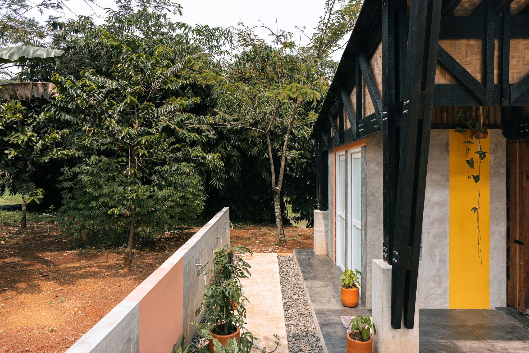 Covered porch with yellow accent wall opening to courtyard with potted plants