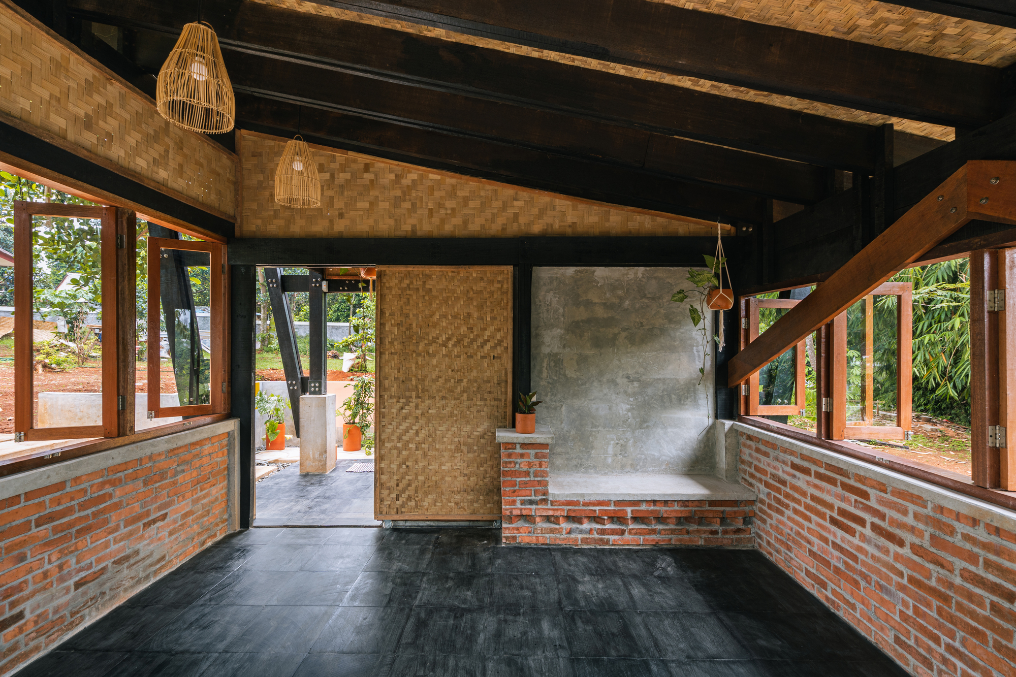 Interior room with woven partition wall and built-in brick seating beneath exposed beams