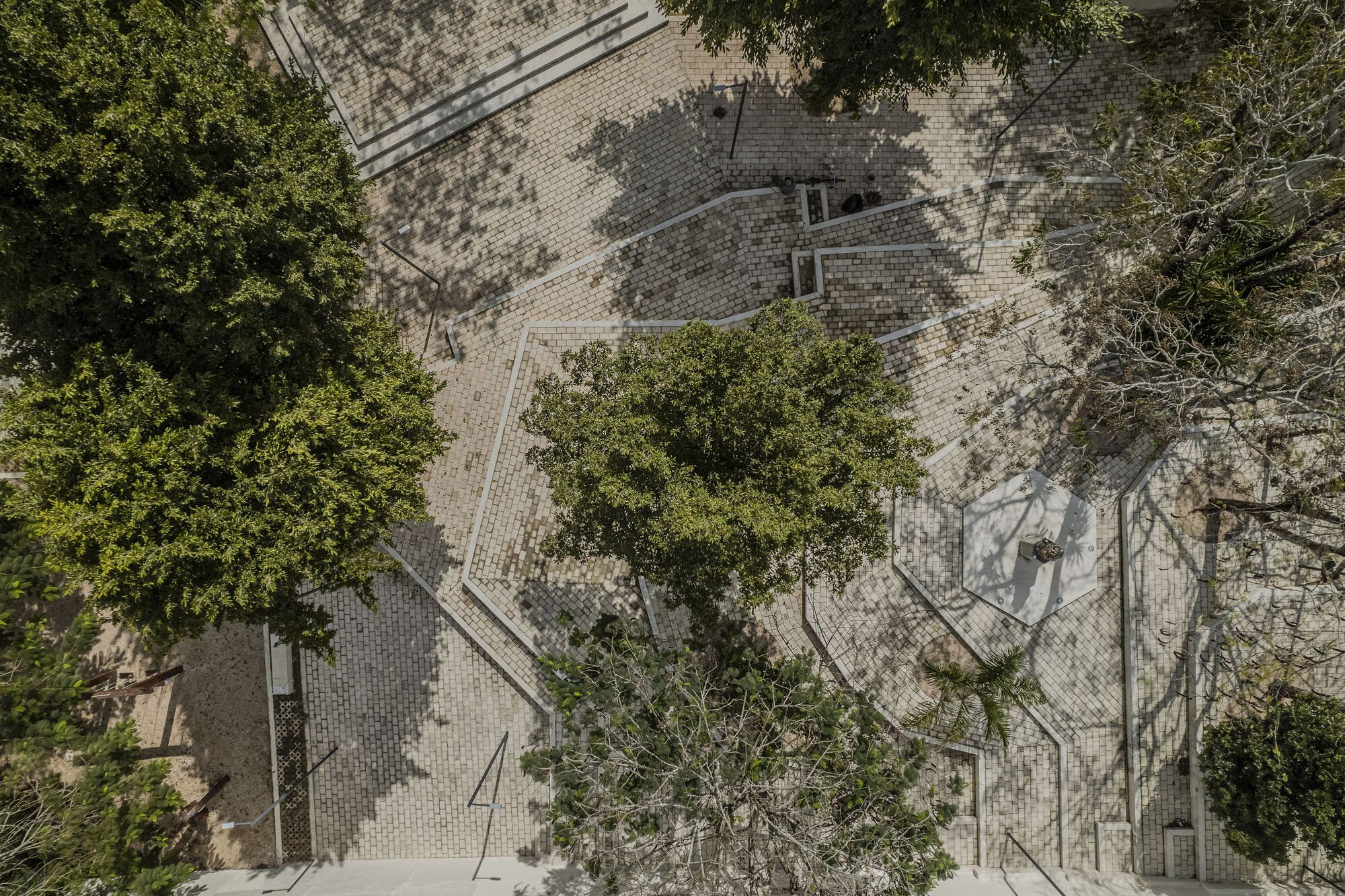 Aerial perspective of courtyard with varied paving textures, preserved mature trees, and geometric walkways