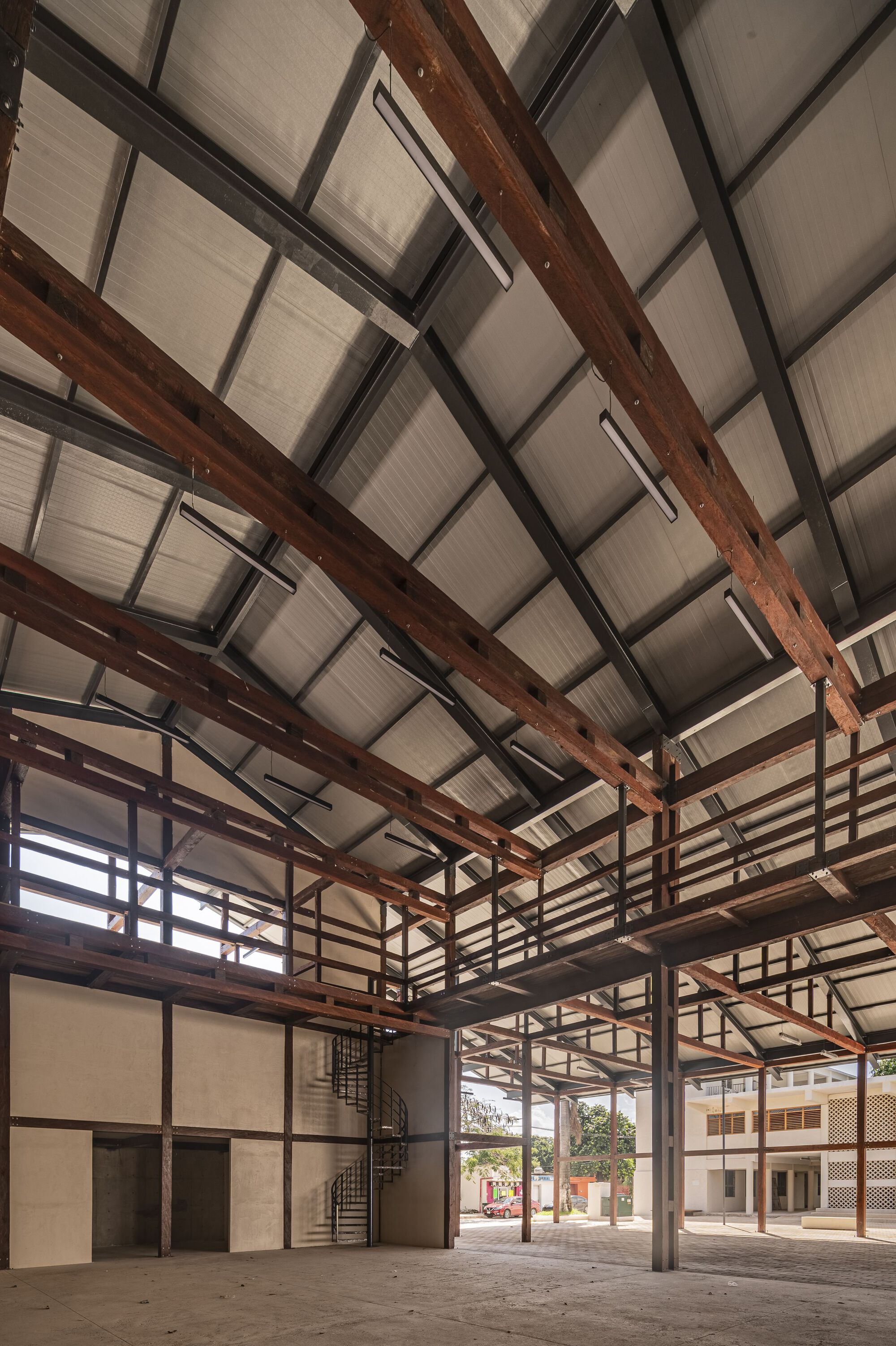 Upward view of the timber and steel roof structure with mezzanine railings and translucent ceiling panels