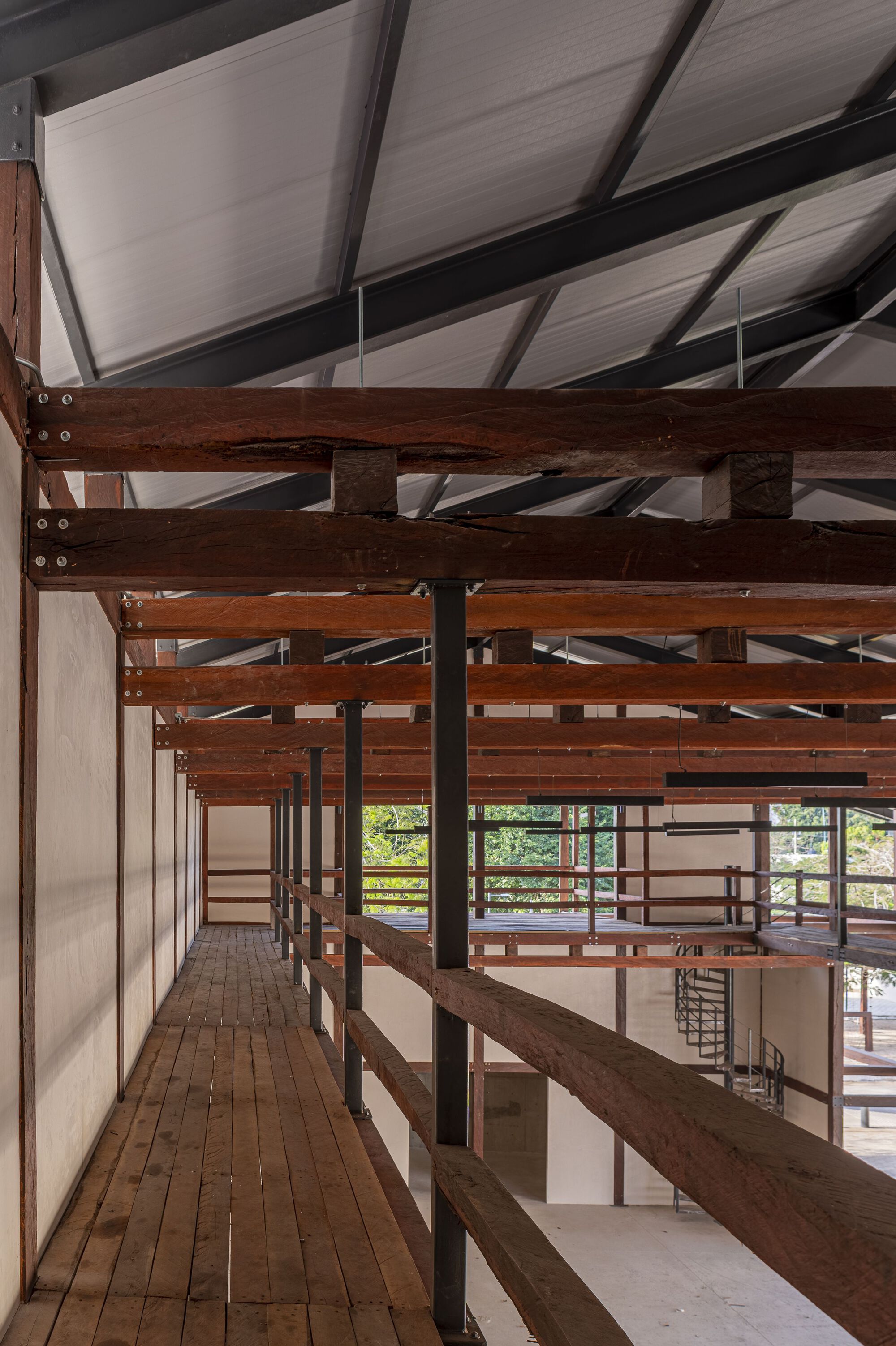 Upper walkway with timber decking and horizontal railings framing views to the landscape beyond