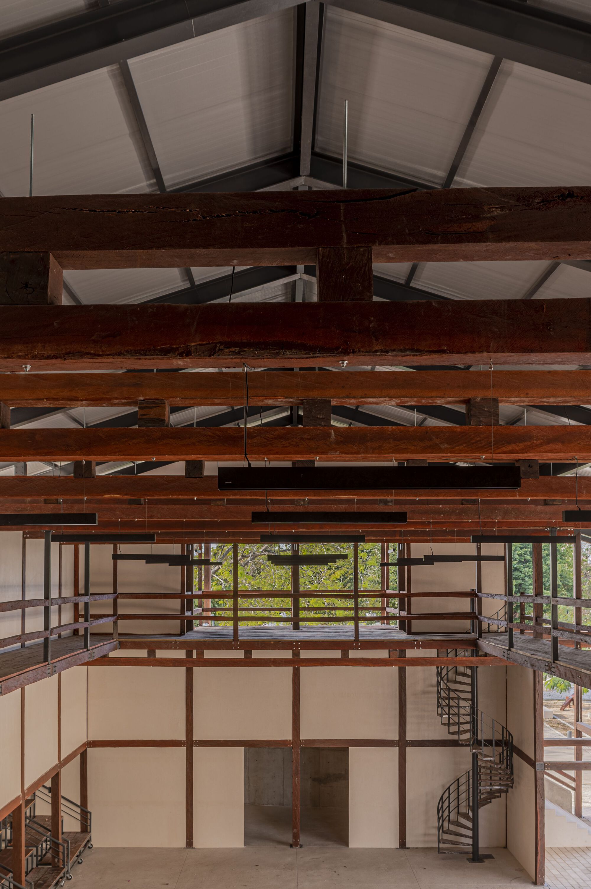 Interior view showing exposed timber beams and joists beneath a translucent ceiling with two spiral staircases below
