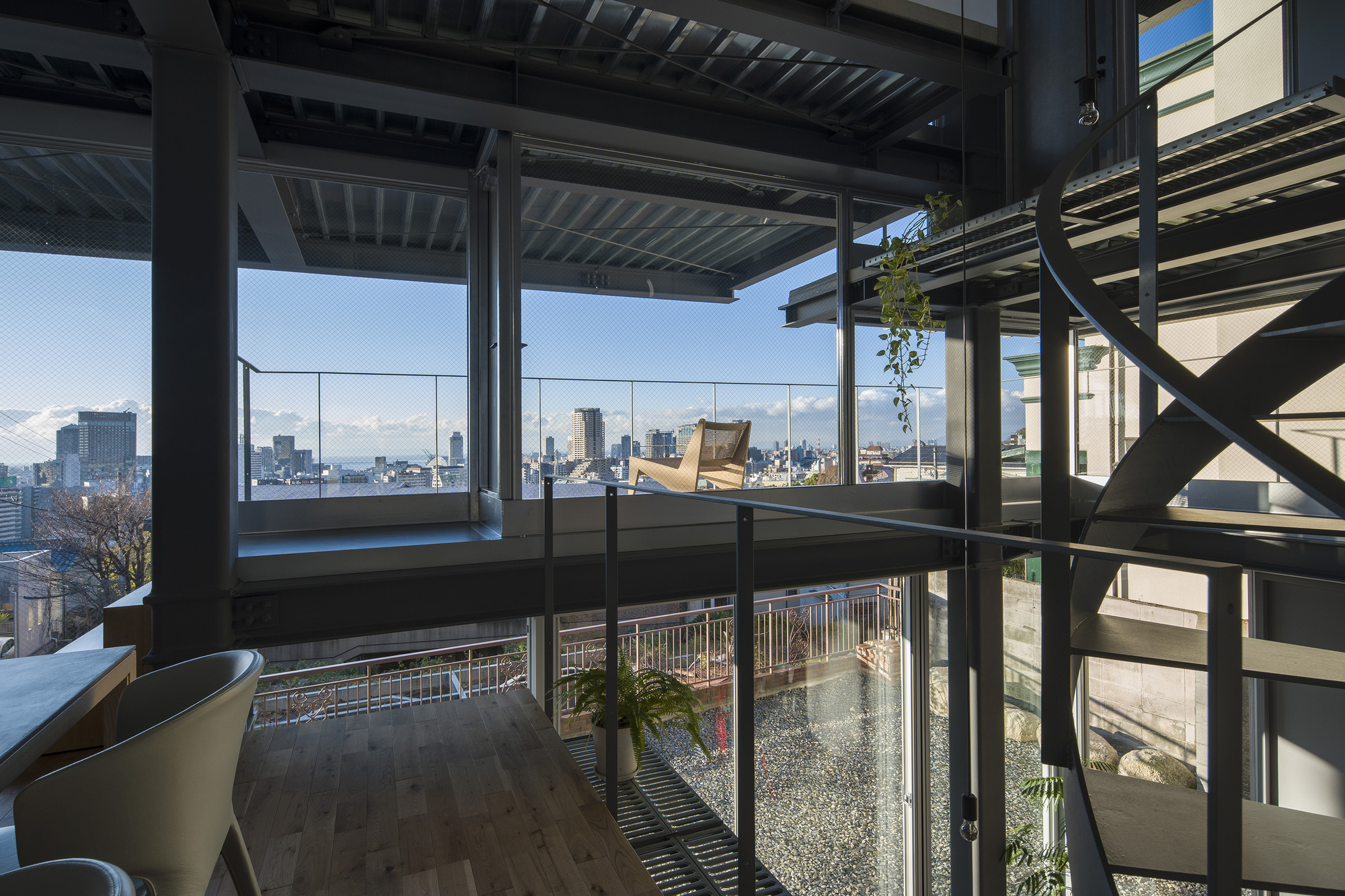 Interior view through steel framing toward the glazed facade and planted rooftop terrace beyond