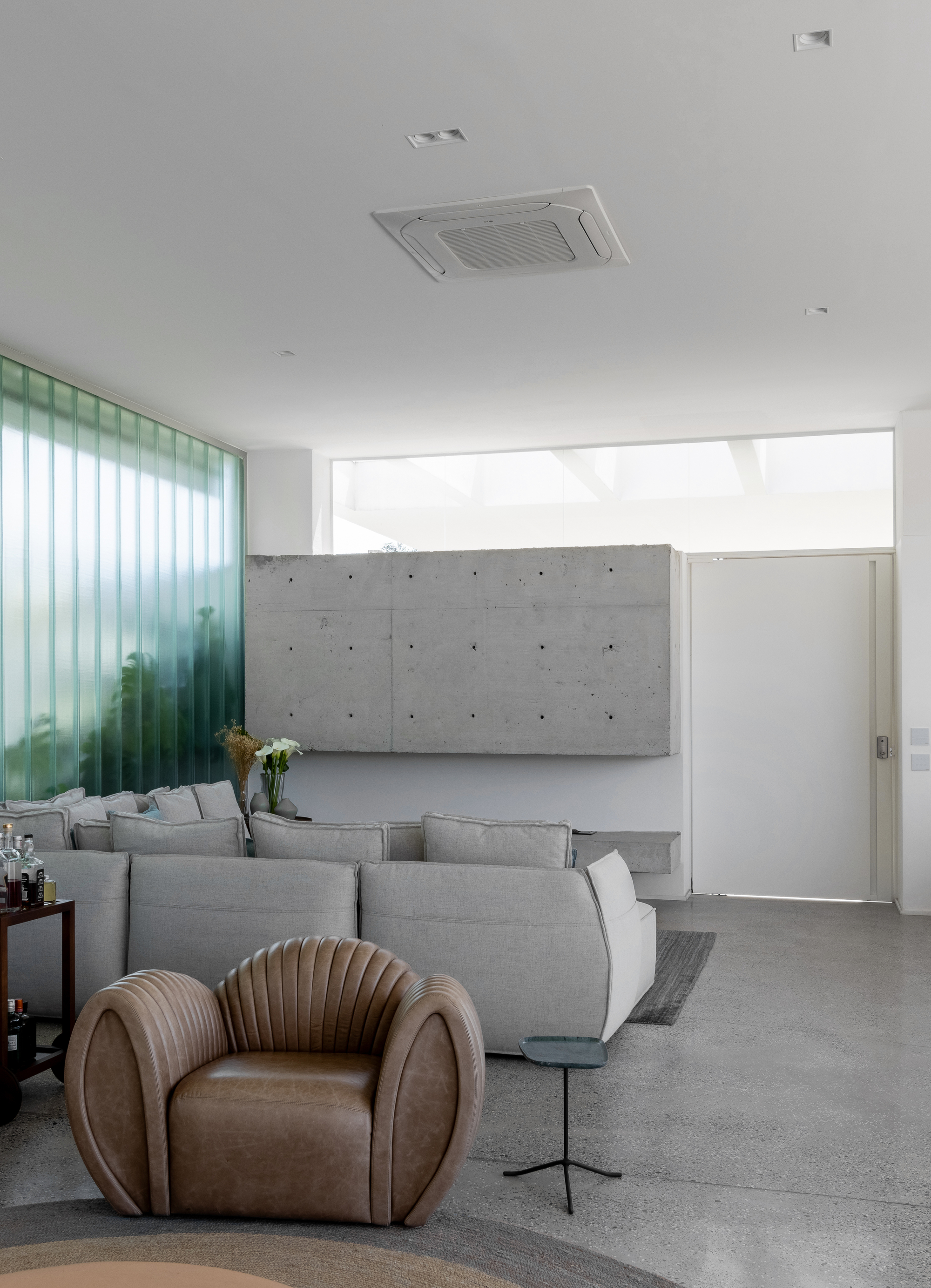 Living room with board-formed concrete panel behind the sofa and clerestory window above