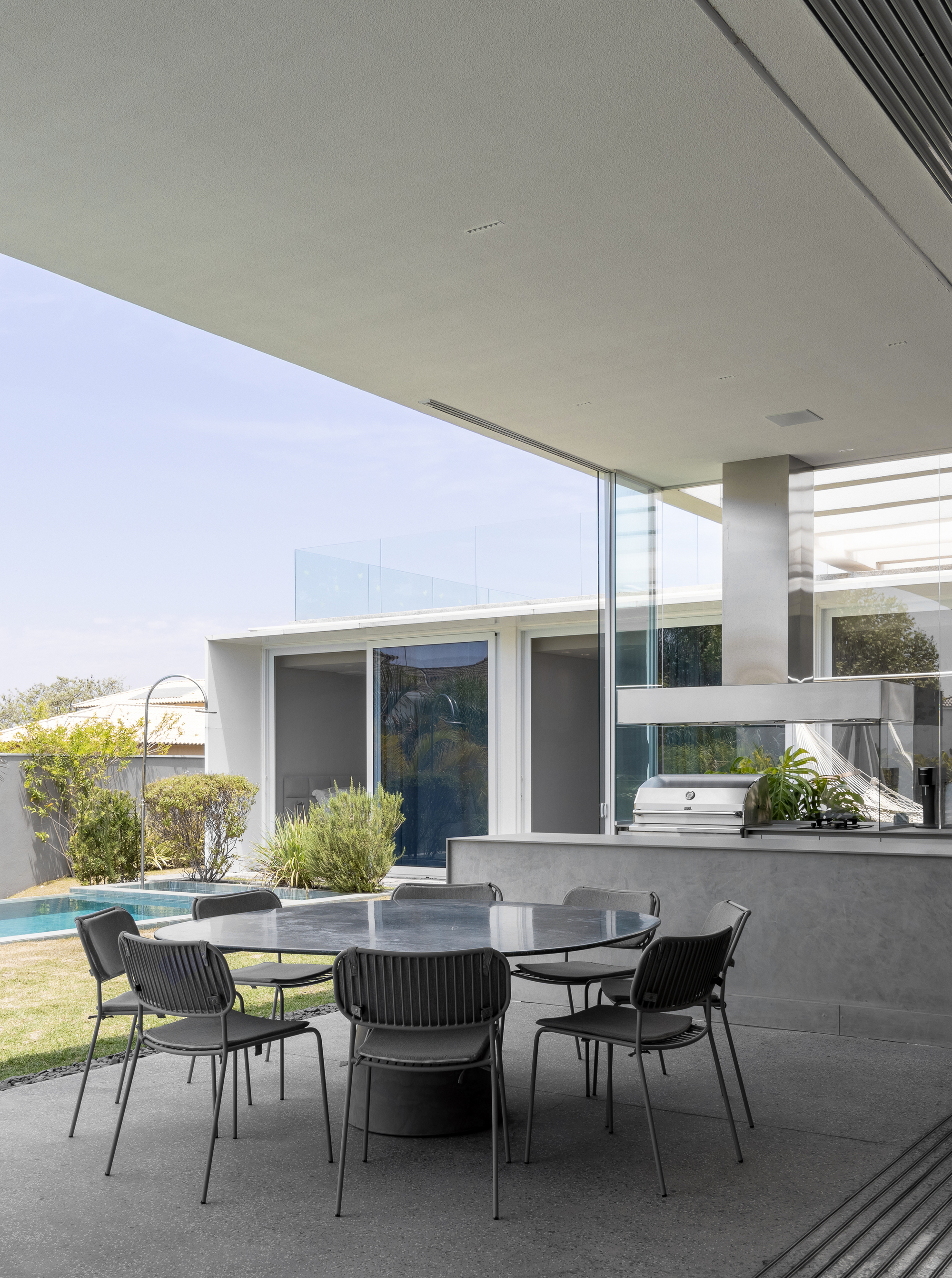 Outdoor dining table under covered terrace looking toward pool and courtyard in daylight