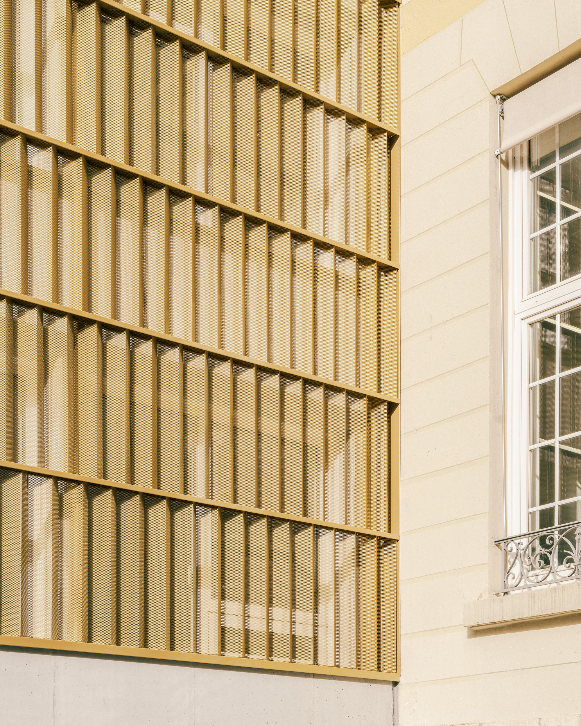 Exterior detail of vertical timber slat facade panels meeting a white horizontal-board wall