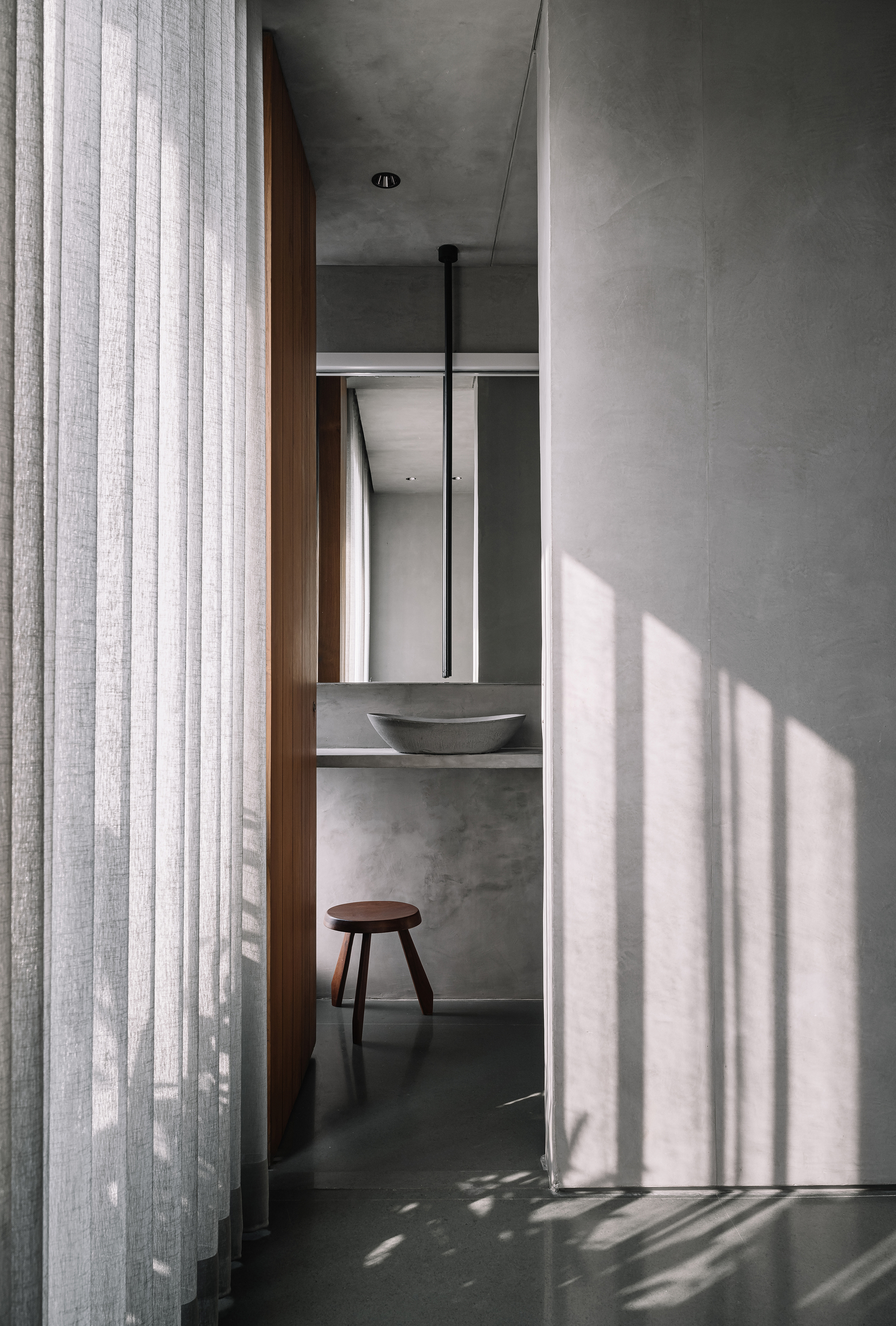 Powder room view through sheer curtains with slatted shadow patterns across dark floor