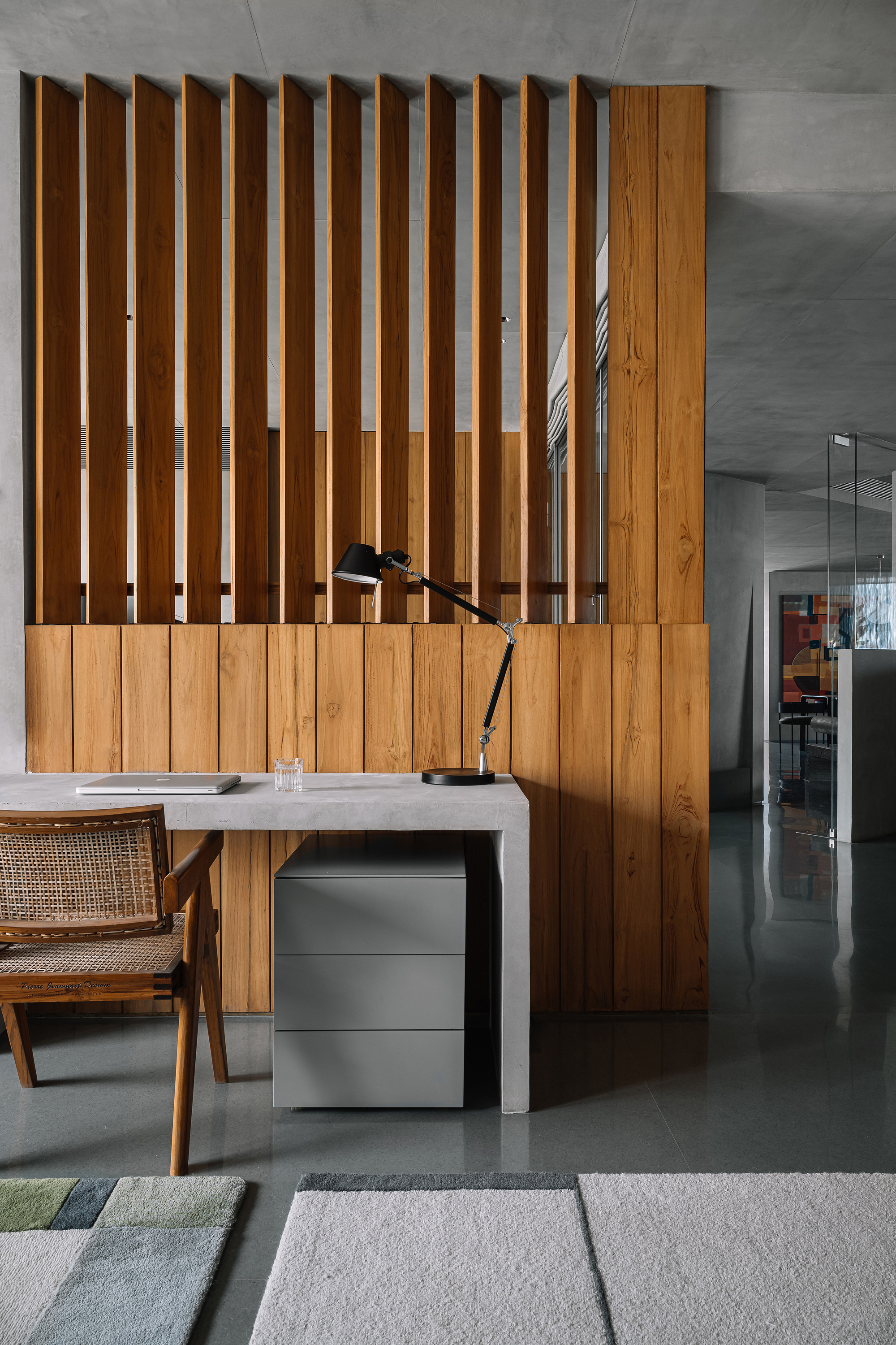 Workspace with timber slat screen divider and concrete desk below exposed ceiling