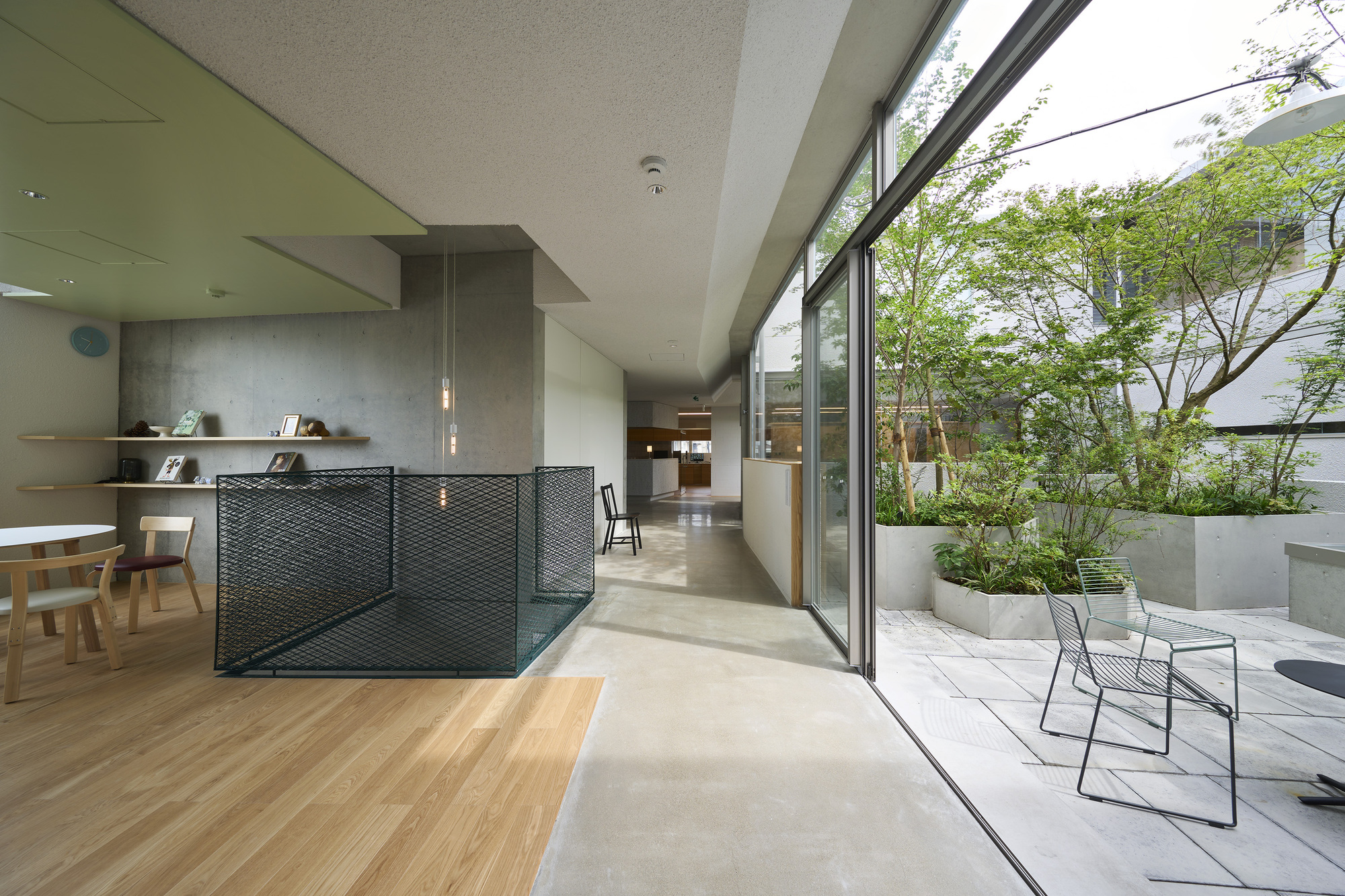 Open-plan interior with perforated metal partition and sliding glass doors opening to a terrace