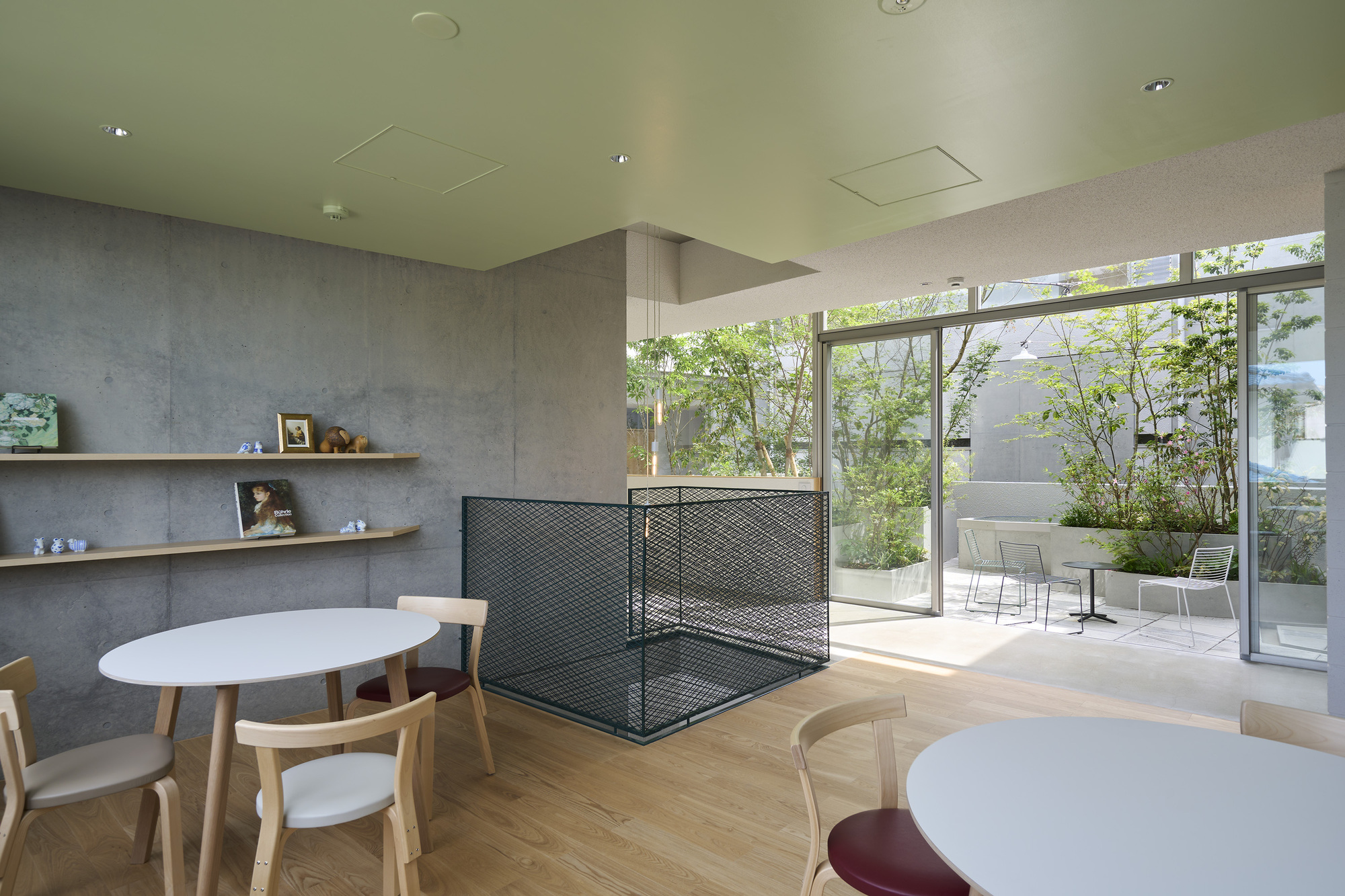 Waiting area with round tables and glazed wall overlooking a terrace with outdoor seating