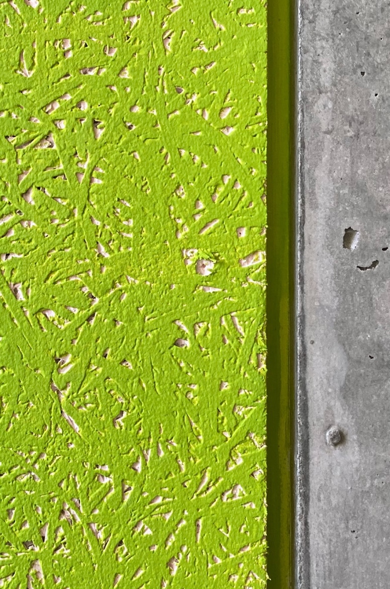 Detail of lime green textured plaster panel meeting raw concrete slab edge with visible formwork holes
