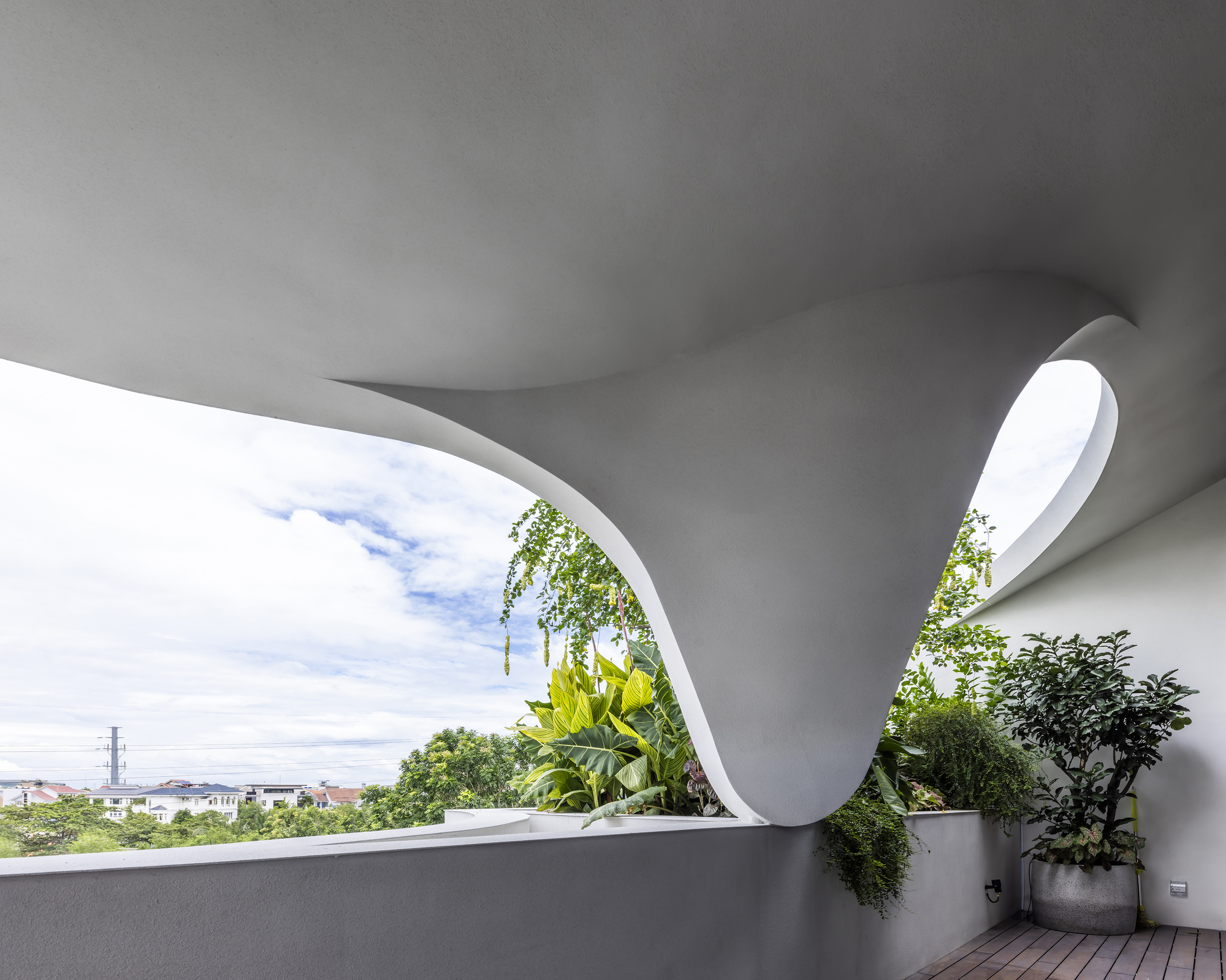 Curved terrace opening with planted pots and timber decking overlooking the neighborhood skyline