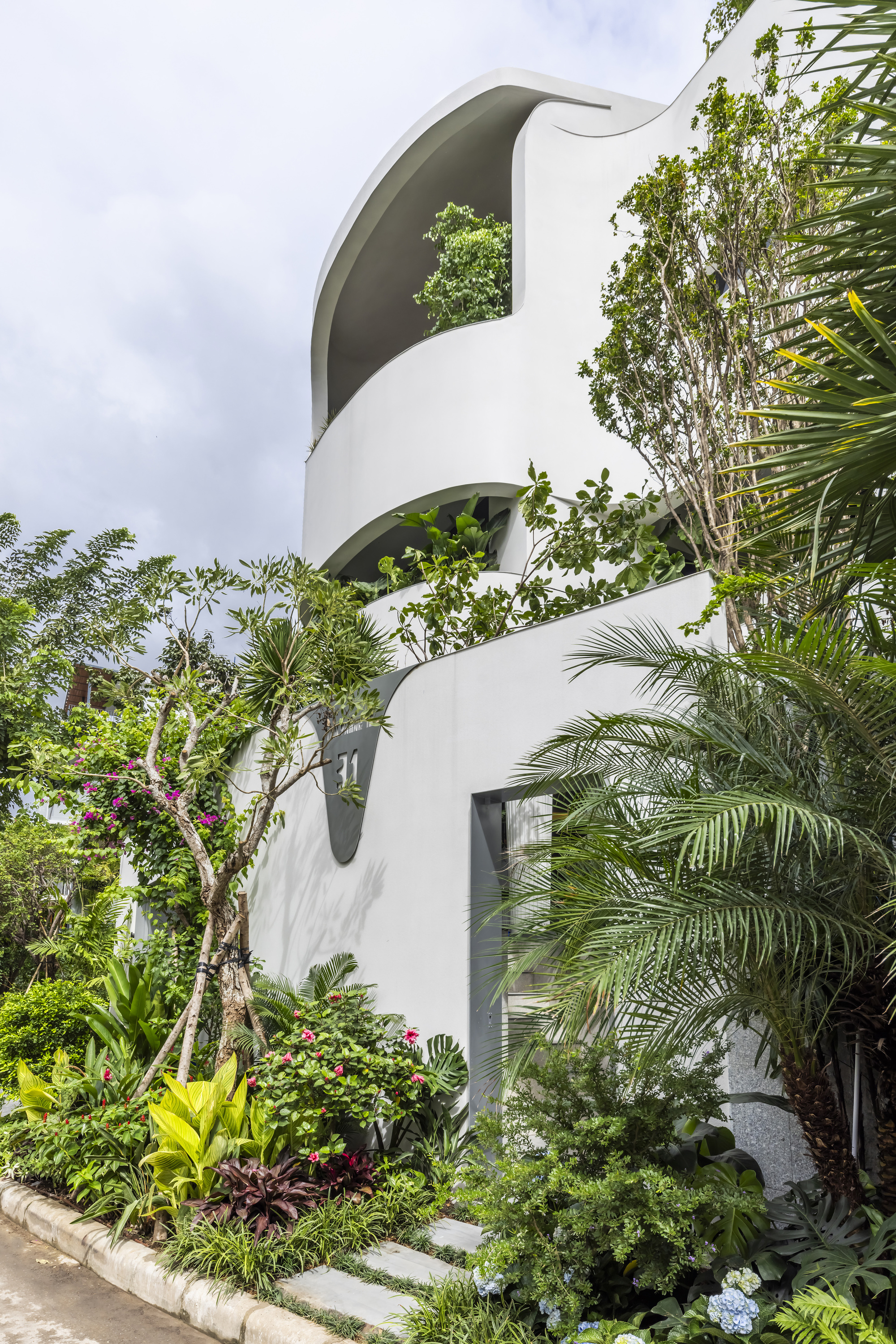 Stacked curving terraces with arched openings surrounded by tropical planting and palm fronds